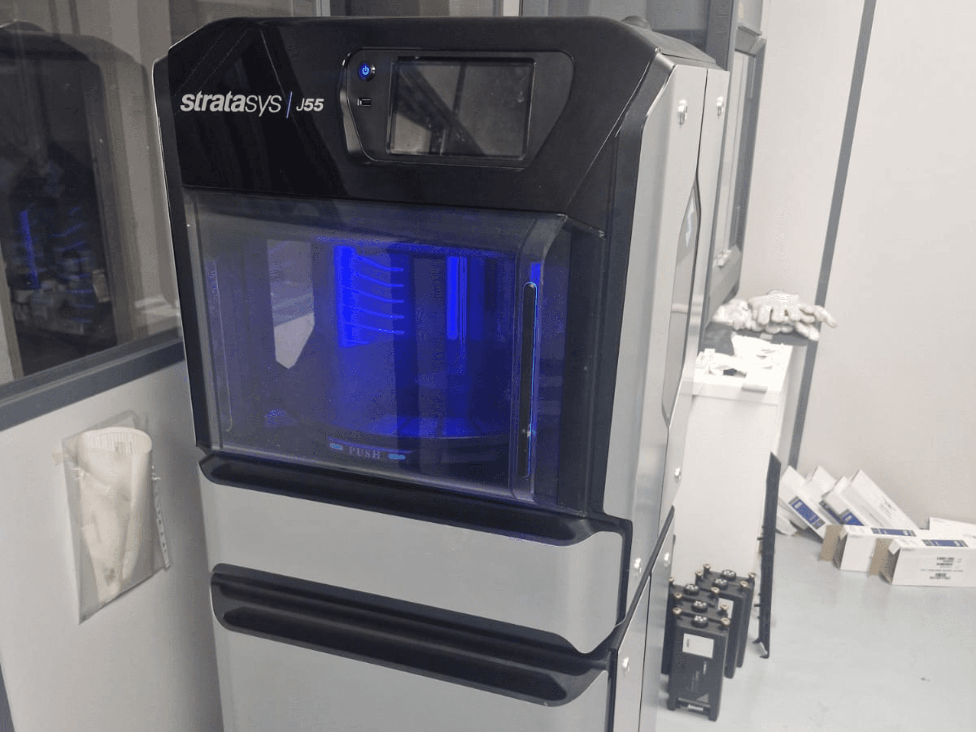 Drukarka 3D do tworzyw sztucznych Stratasys J55 Prime w widoku z boku, prezentująca elegancką konstrukcję i podświetlany obszar drukowania.