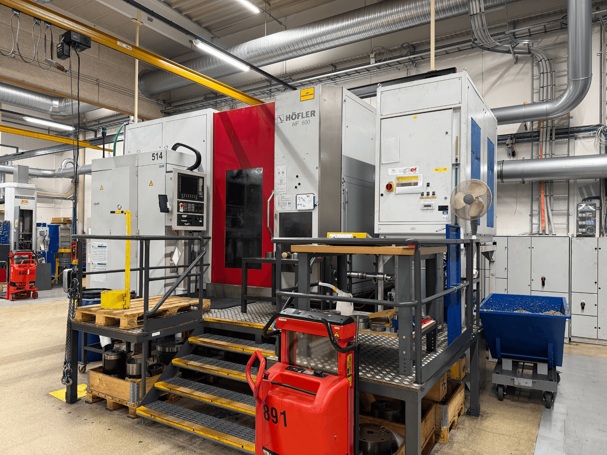 Obrabiarka HOFLER HF 600, widok z boku, pokazujący panel sterowania, żółtą barierę bezpieczeństwa i otoczenie warsztatu.