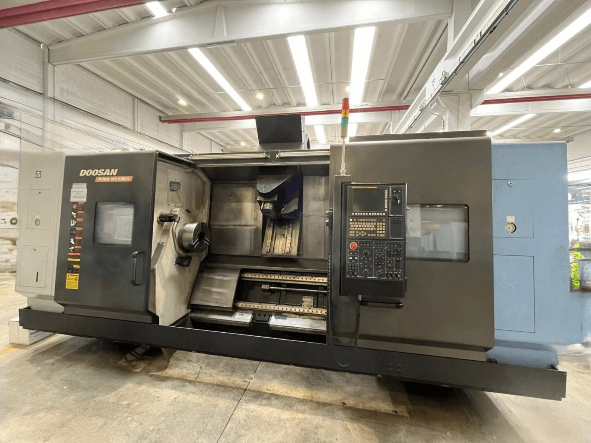 Widok z przodu poziomej tokarki DOOSAN PUMA MX3100 z panelem sterowania oraz widocznym wrzecionem i obszarem uchwytu narzędziowego.