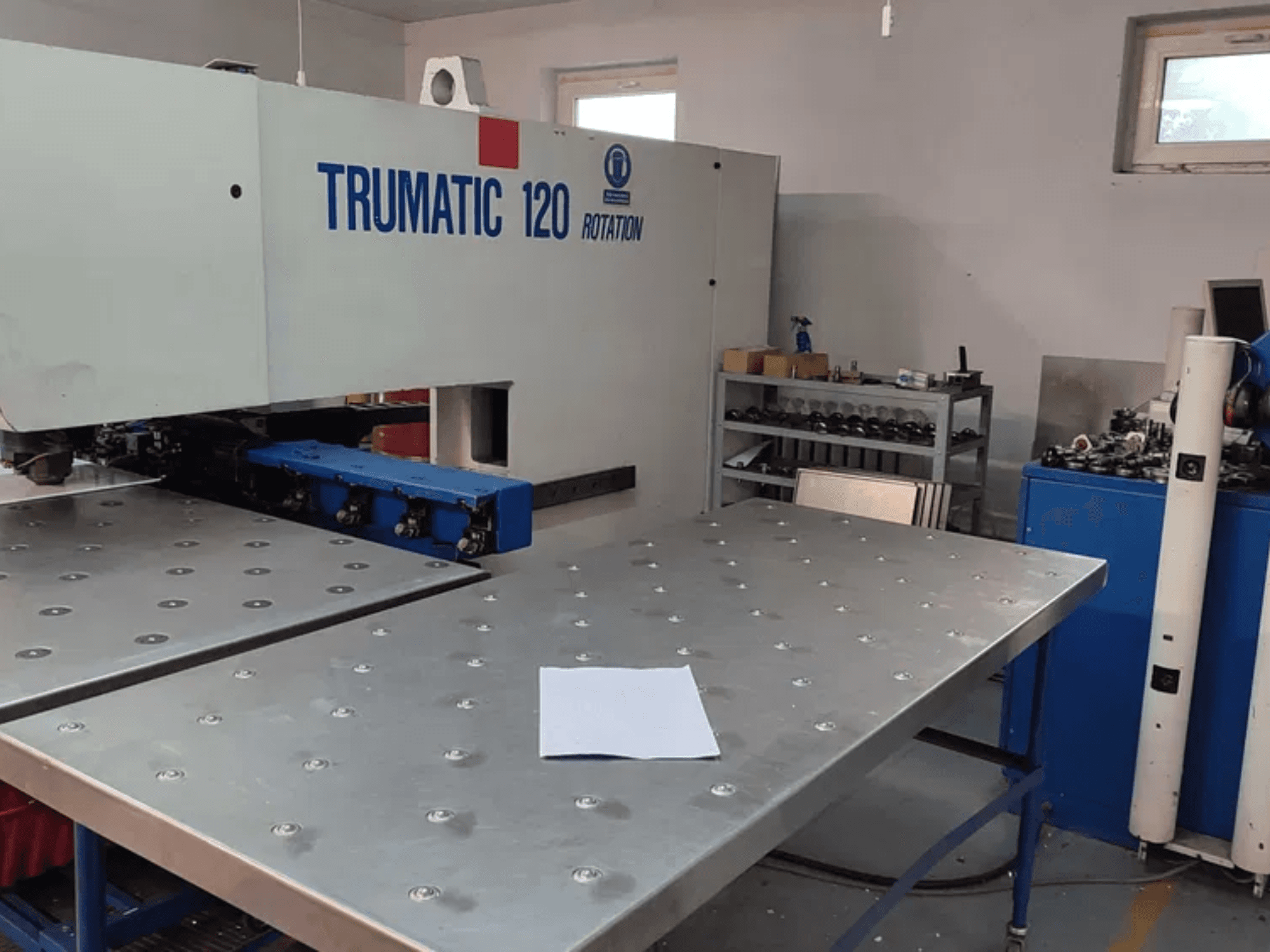 Wykrawarka CNC TRUMPF TRUMATIC 120R widziana od przodu, z metalowym stołem z wykrojonymi otworami i pustym arkuszem.