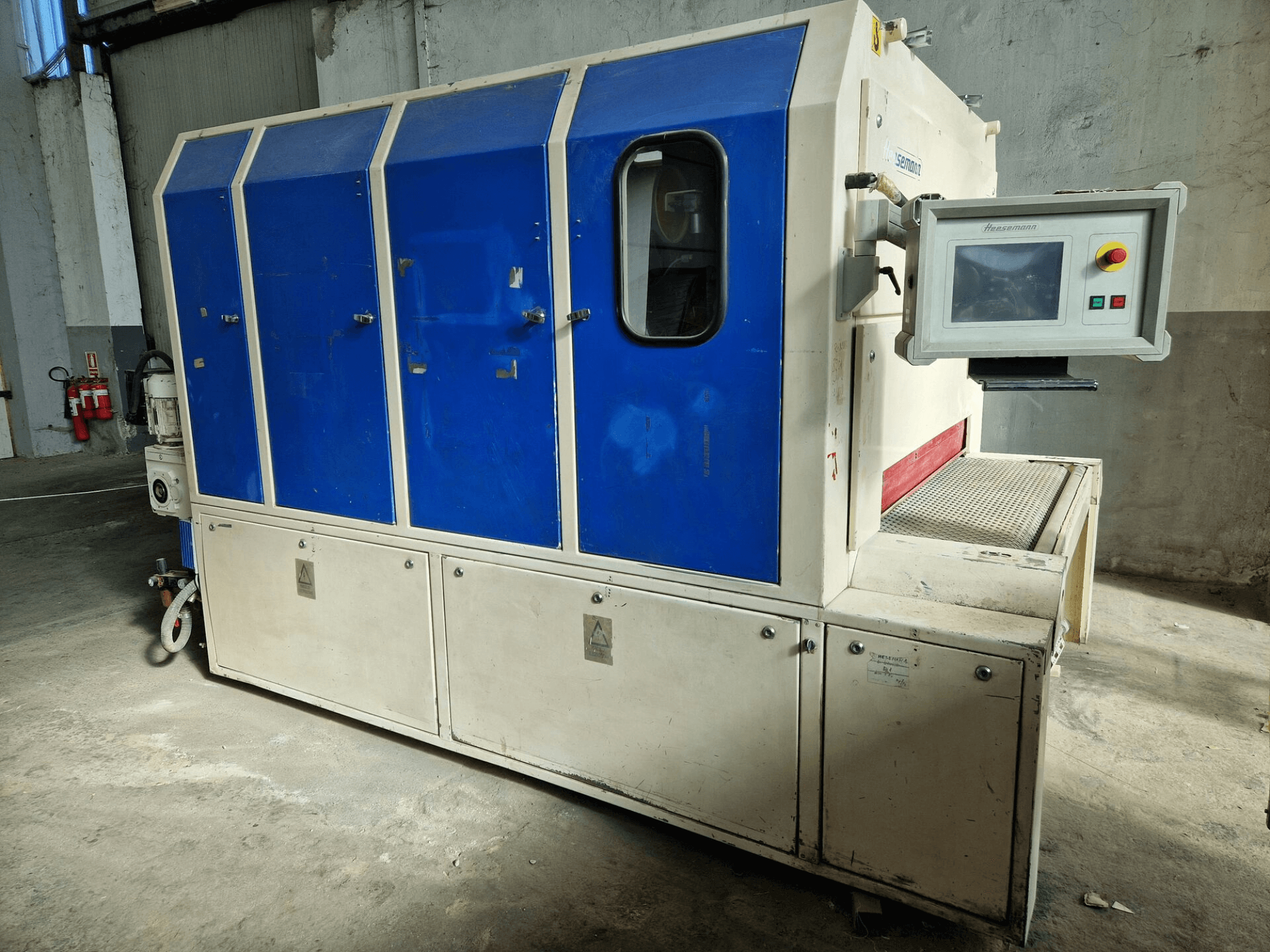 Maszyna przemysłowa marki "Sedecom", widok z boku; posiada niebieskie panele, ekran sterowania i teksturowaną powierzchnię do przenoszenia produktów.