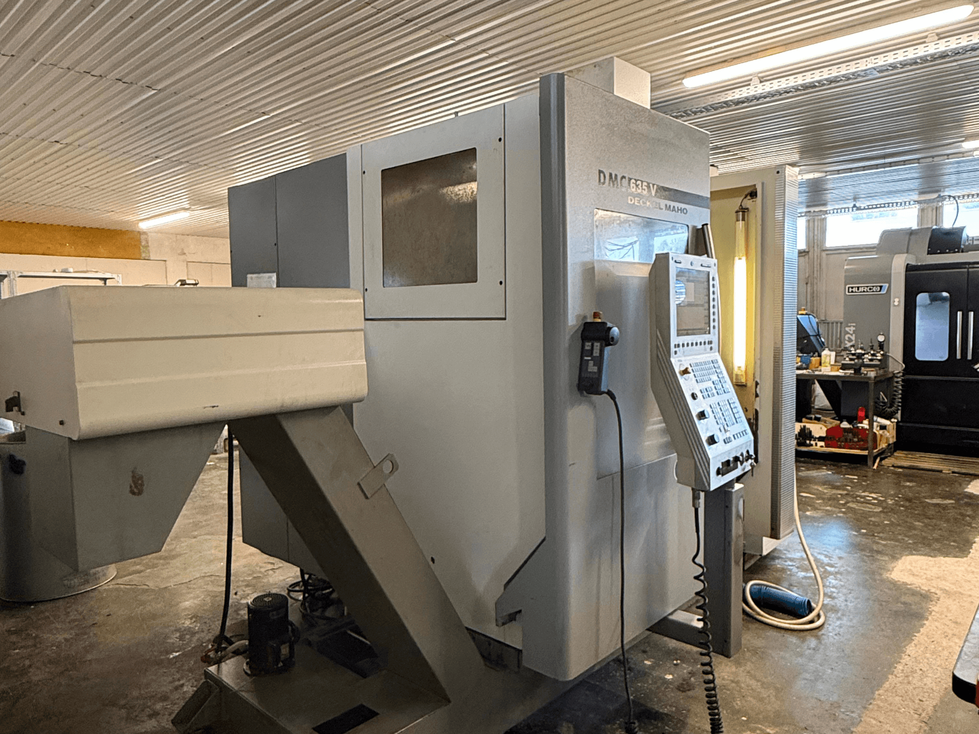 Frezarka DMC G635V w warsztacie, widok z przodu z widocznym panelem sterowania i podłączonymi elektronarzędziami.
