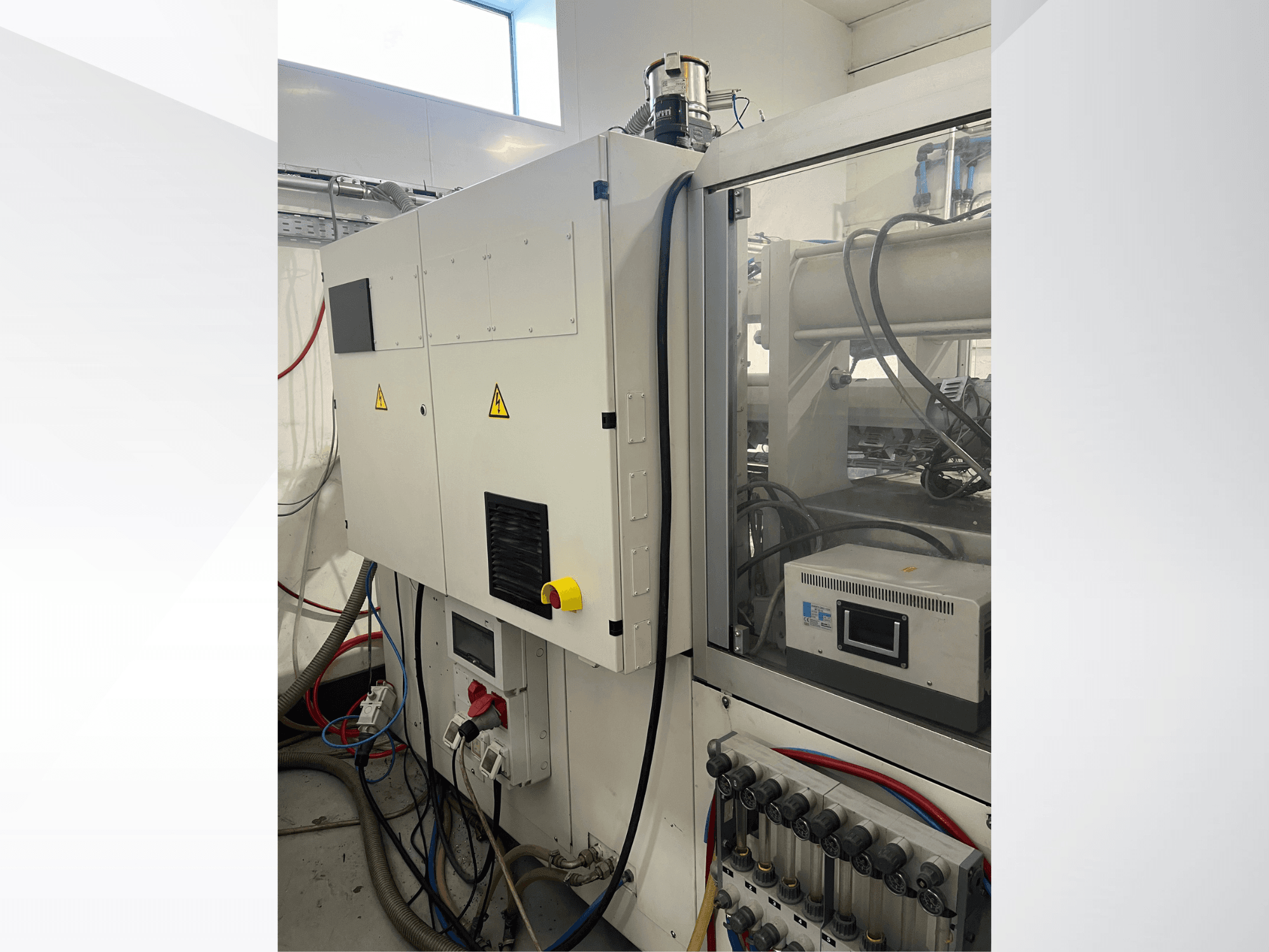 Hydrauliczna wtryskarka Krauss Maffei 125-520 C1 – widok z boku przedstawiający panel sterowania i przyłącza hydrauliczne.