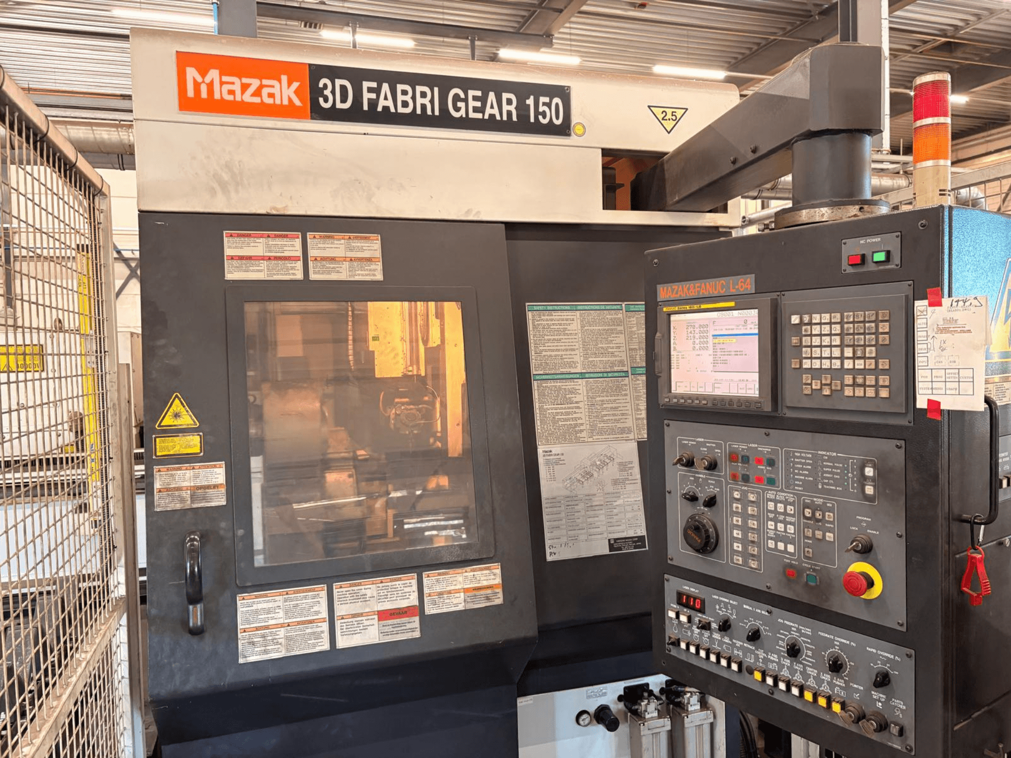 Maszyna do cięcia rur Mazak 3D Fabri Gear 150 – widok z przodu przedstawiający panel sterowania, etykiety bezpieczeństwa oraz interfejs operacyjny.