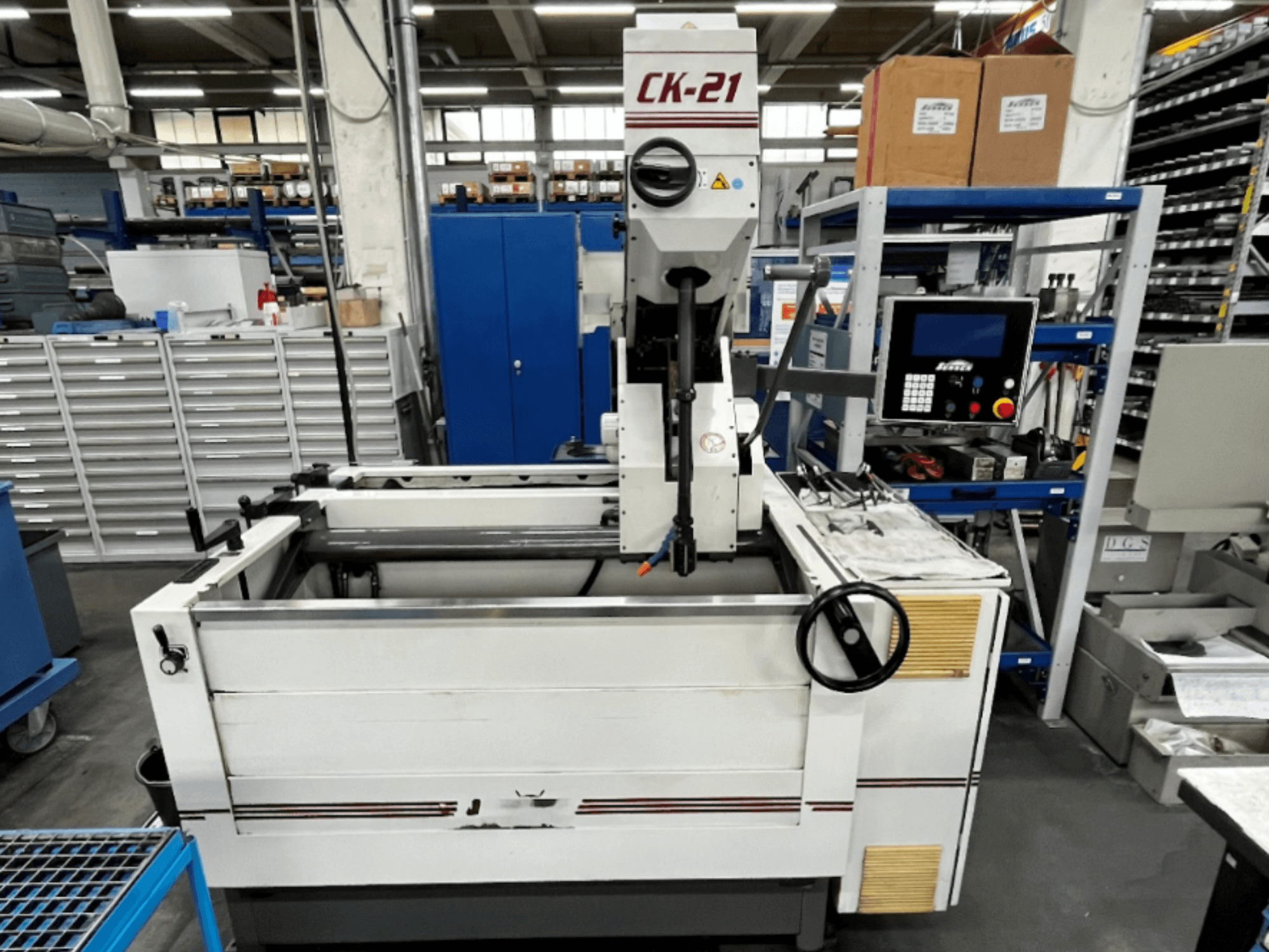 Maszyna do honowania pionowego Sunnen CK-21-CC w widoku z przodu, z elementami sterującymi, obszarem honowania i sprzętem pomocniczym w tle.