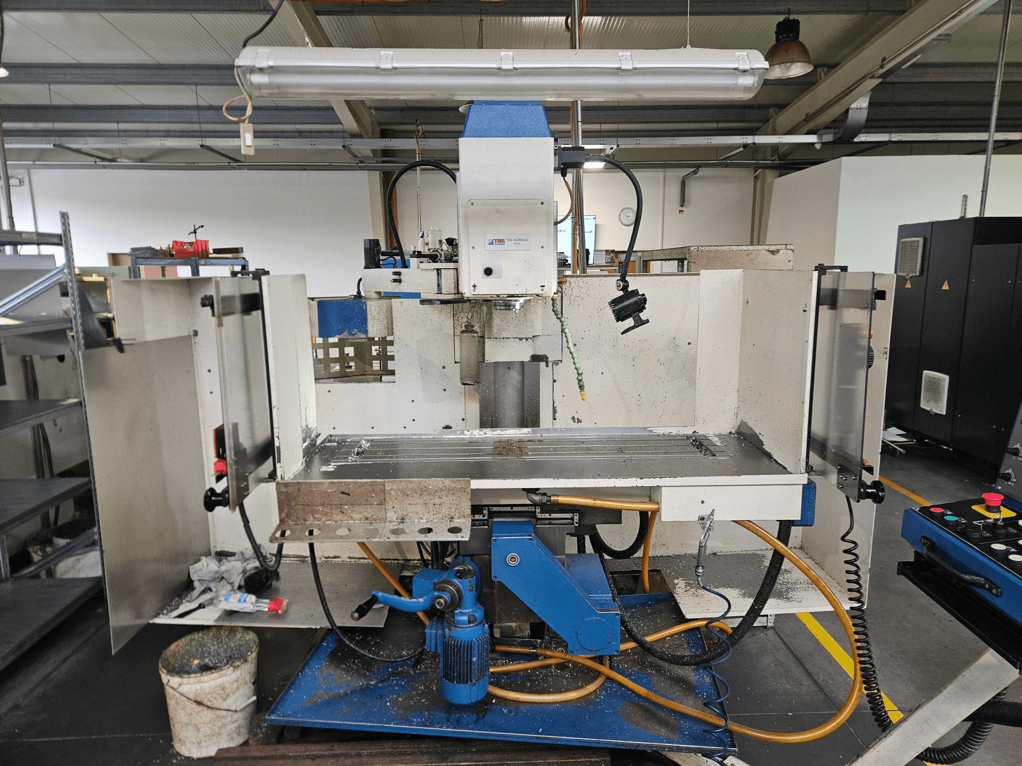 TOS Olomouc FV30 CNC Pionowe centrum obróbcze w warsztacie, widok z przodu przedstawiający panel sterowania, stół roboczy i układ chłodzenia.