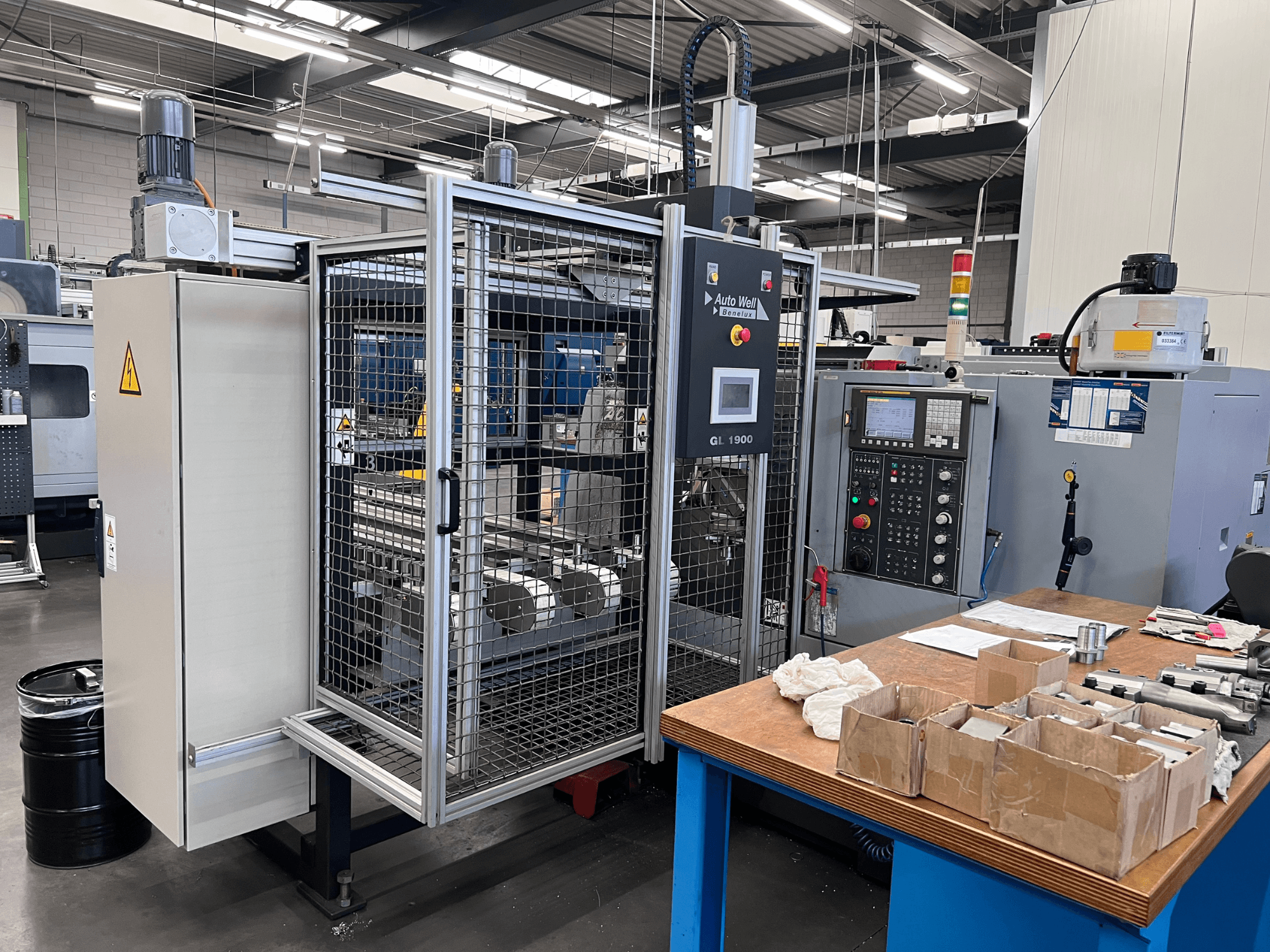 Widok z przodu urządzenia Auto Weld GL 1900 z panelem sterowania, obudową bezpieczeństwa i narzędziami na stole warsztatowym.