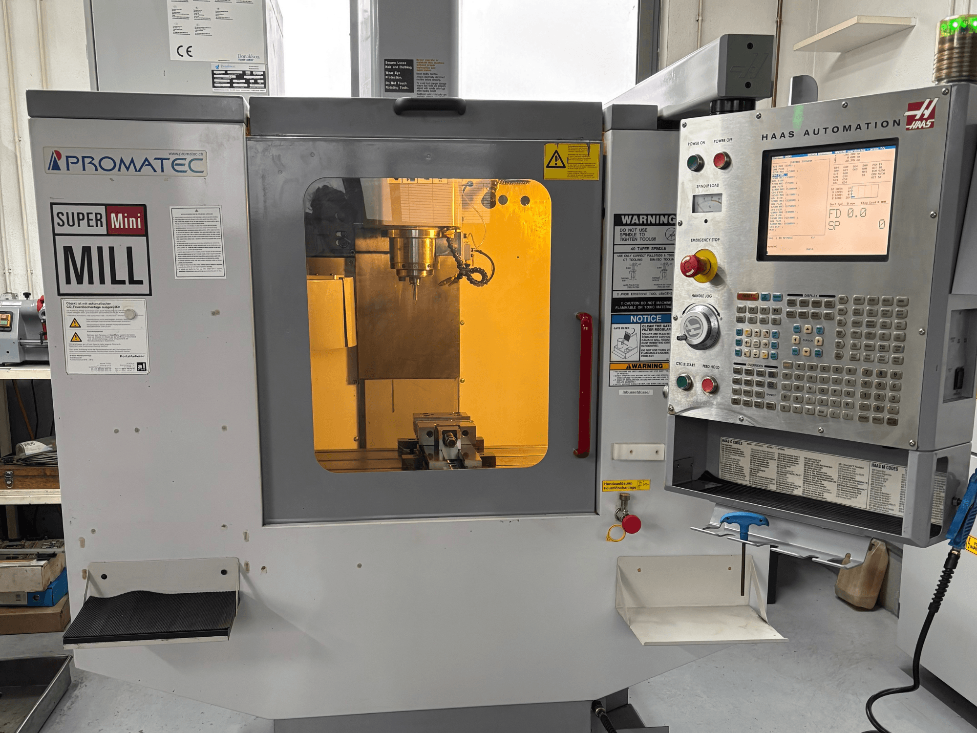 Promatec Super Mini Mill w widoku z przodu, wyposażony w panel sterowania Haas Automation i widoczne narzędzie tnące wewnątrz.