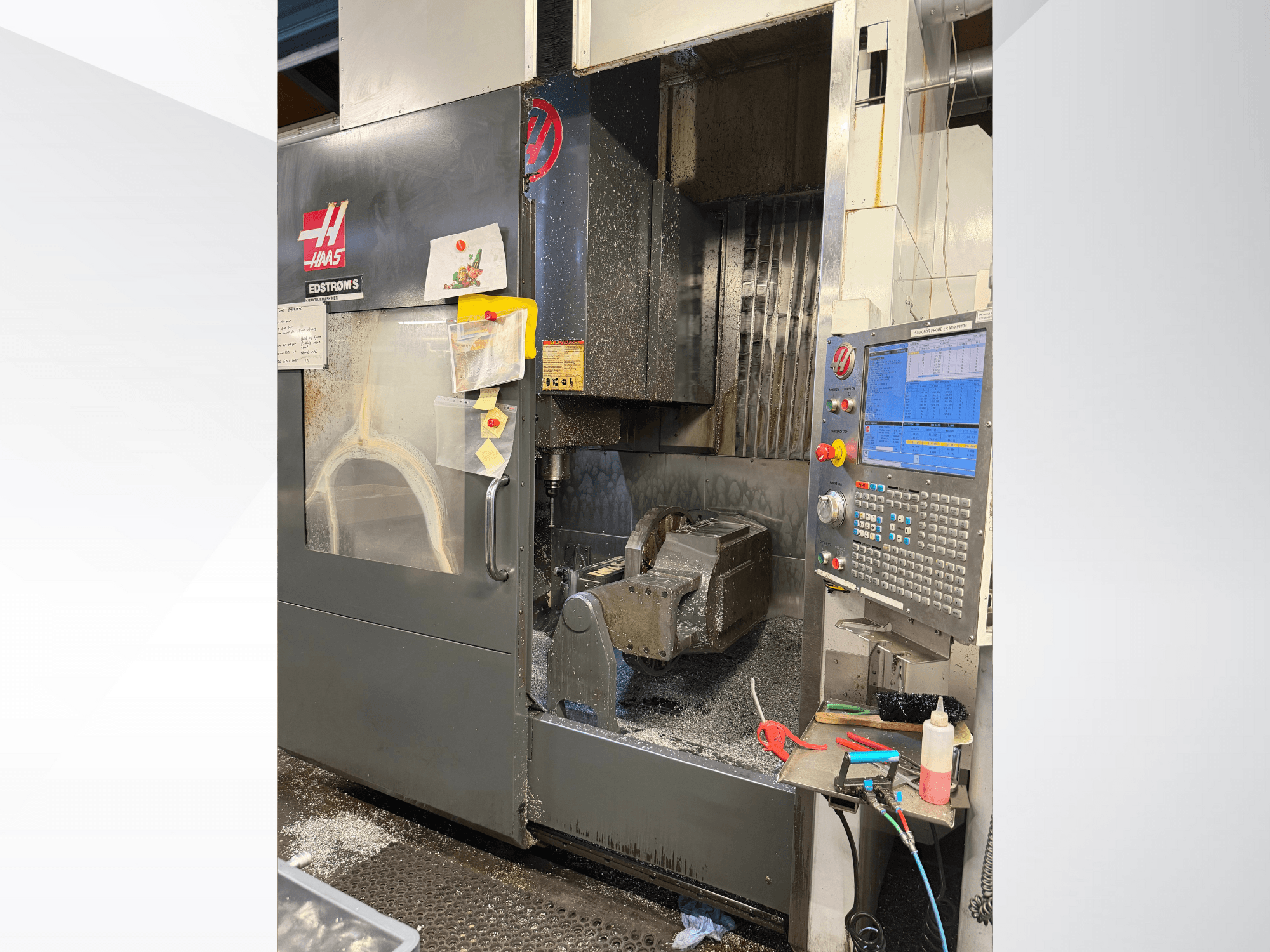 Maszyna CNC Haas model EDSTROM S, widok z przodu, pokazujący metalowy przedmiot obrabiany, panel sterowania i metalowe wióry wewnątrz.