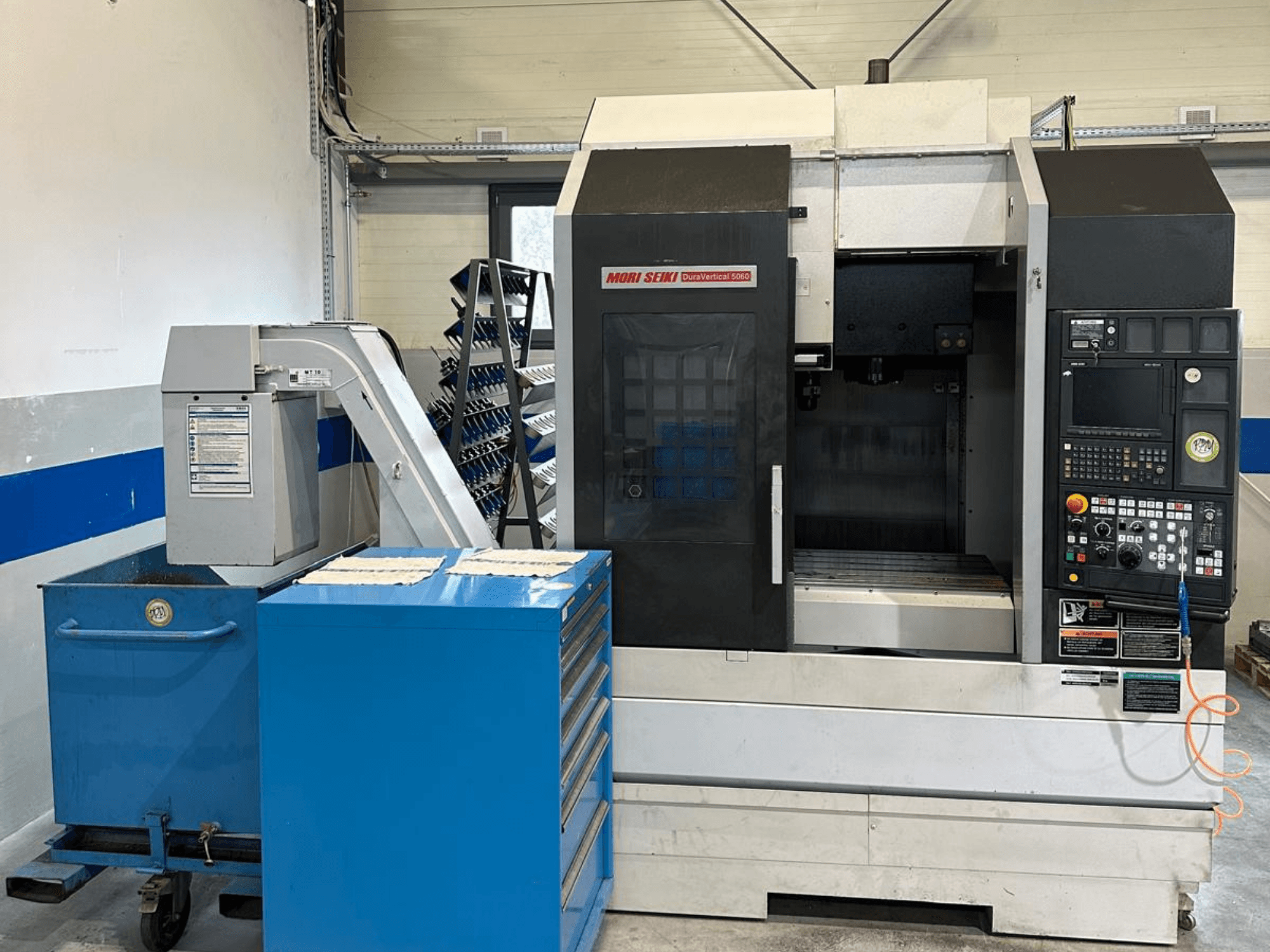 MORI SEIKI DURA VERTICAL 5060 – widok z przodu pionowego centrum obróbczego z panelem sterowania i znajdującym się obok magazynem narzędzi.