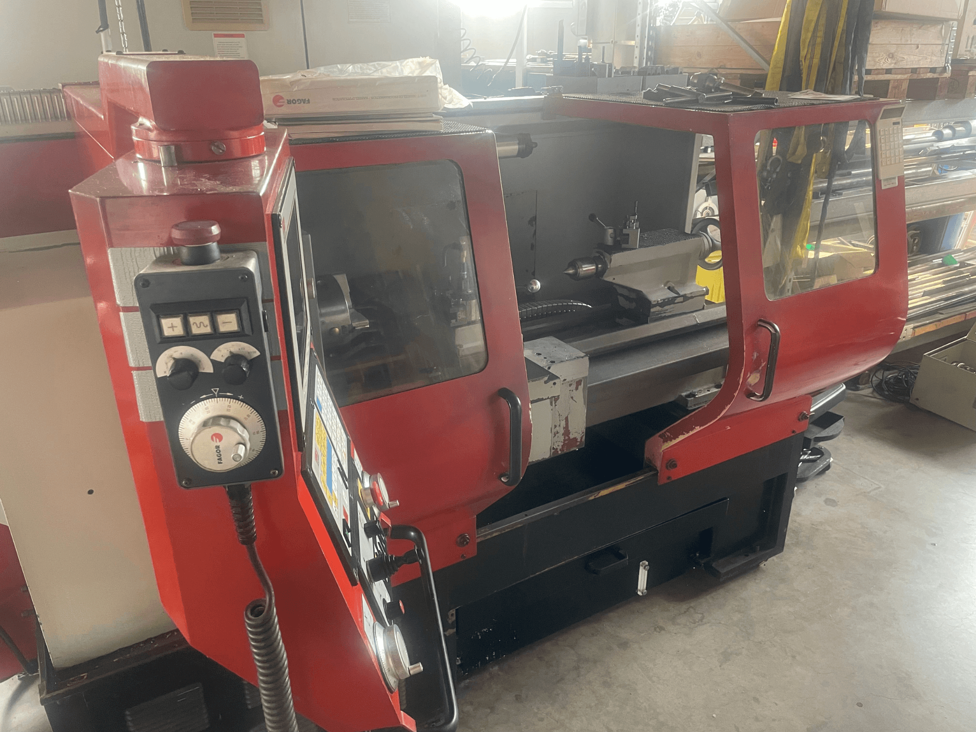 Tokarka pozioma EMCO EMCOMAT 200X1000, widok z boku, przedstawiający elementy sterujące, obudowę z okienkiem oraz konfigurację tokarki.