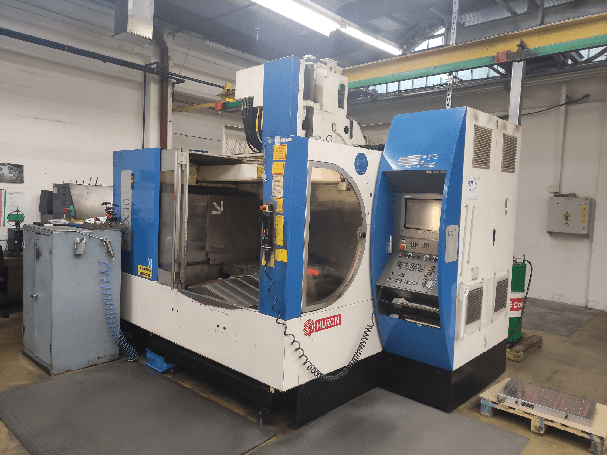 Maszyna CNC HURON KX10 w warsztacie, widok z przodu, z panelem sterowania i dużym otworem do obróbki.