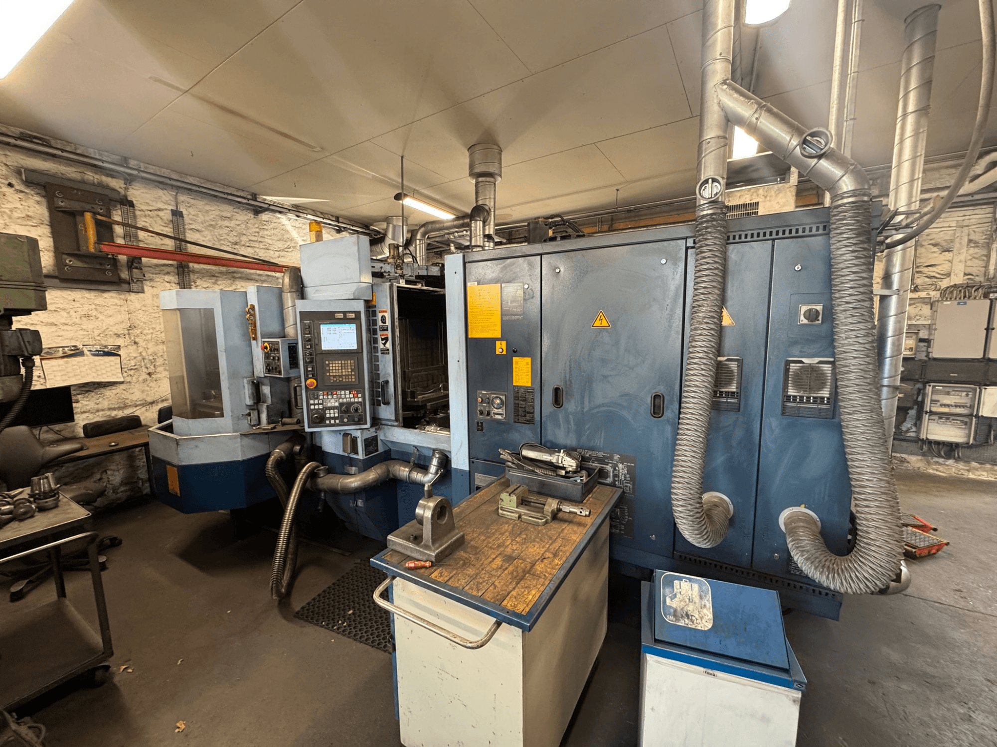 Poziome centrum obróbcze Matsuura H.PLUS-300 w warsztacie, widok z przodu, przedstawiający panel sterowania i stół roboczy.