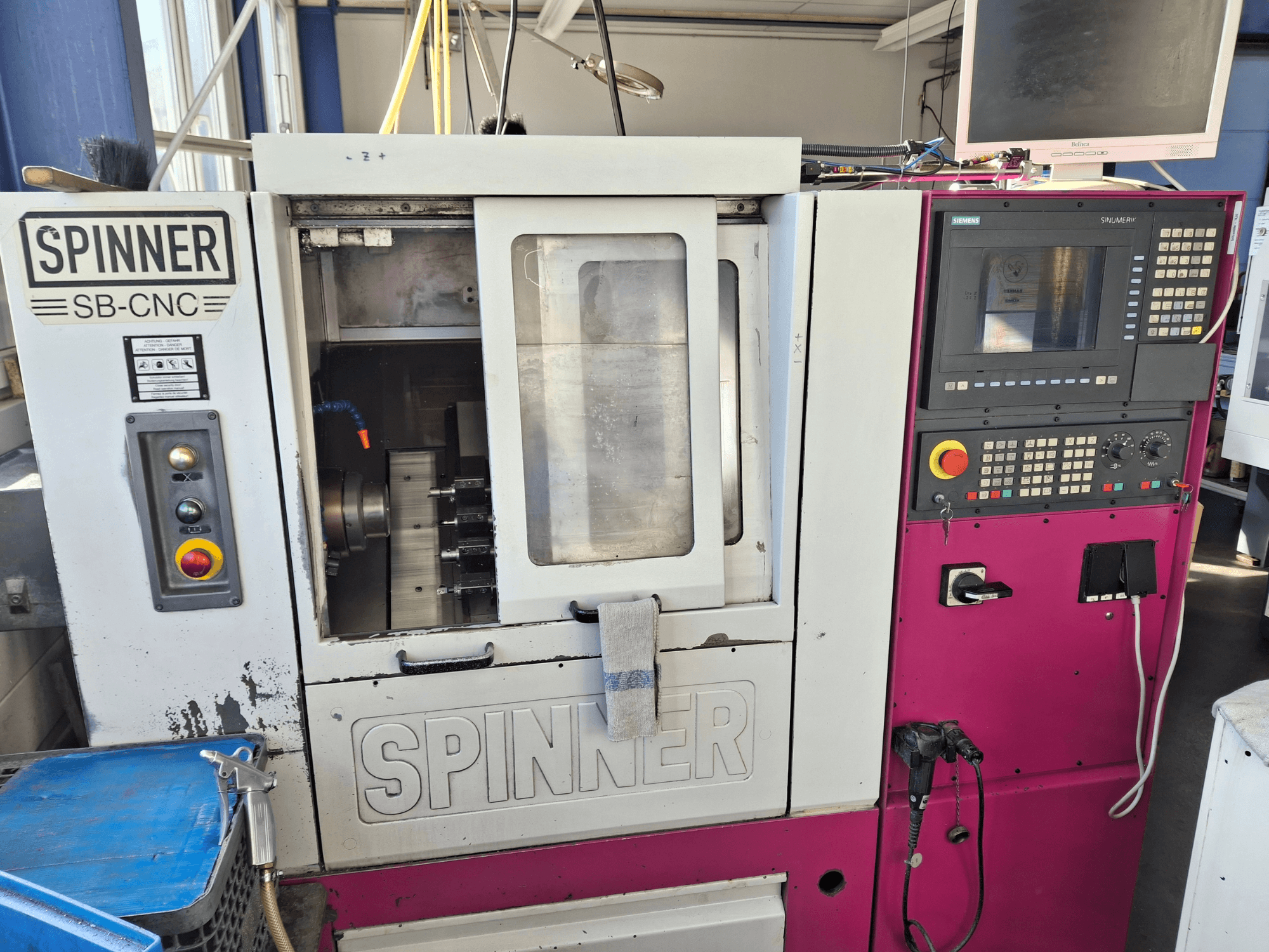 Tokarka pozioma SPINNER SB-CNC, widok z przodu pokazujący panel sterowania, uchwyt narzędziowy i wskaźniki operacyjne.