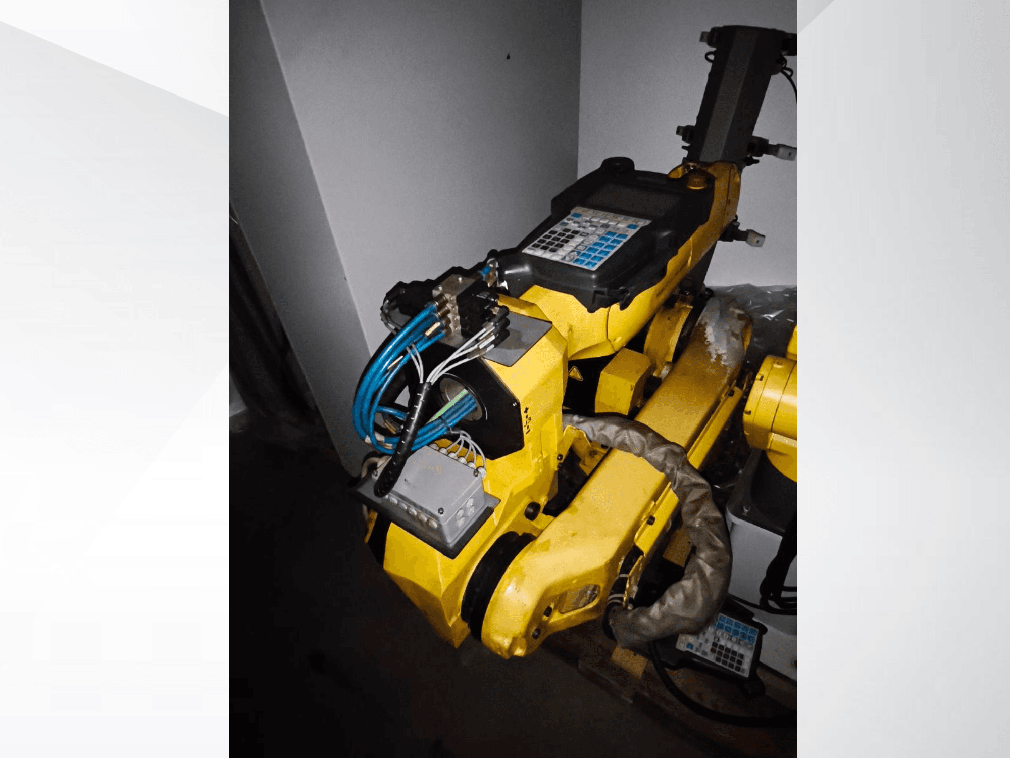 Ramię robota FANUC M-20iA w widoku z boku, z żółtym korpusem, panelem sterowania i podłączonym okablowaniem.