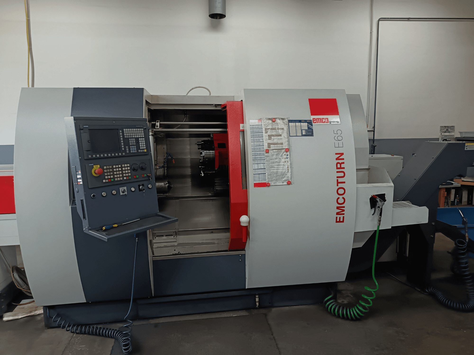 Centrum frezarskie EMCO EMCOTURN E65, widok z przodu przedstawiający panel sterowania, mechanizm wewnętrzny i funkcje w warunkach warsztatowych.