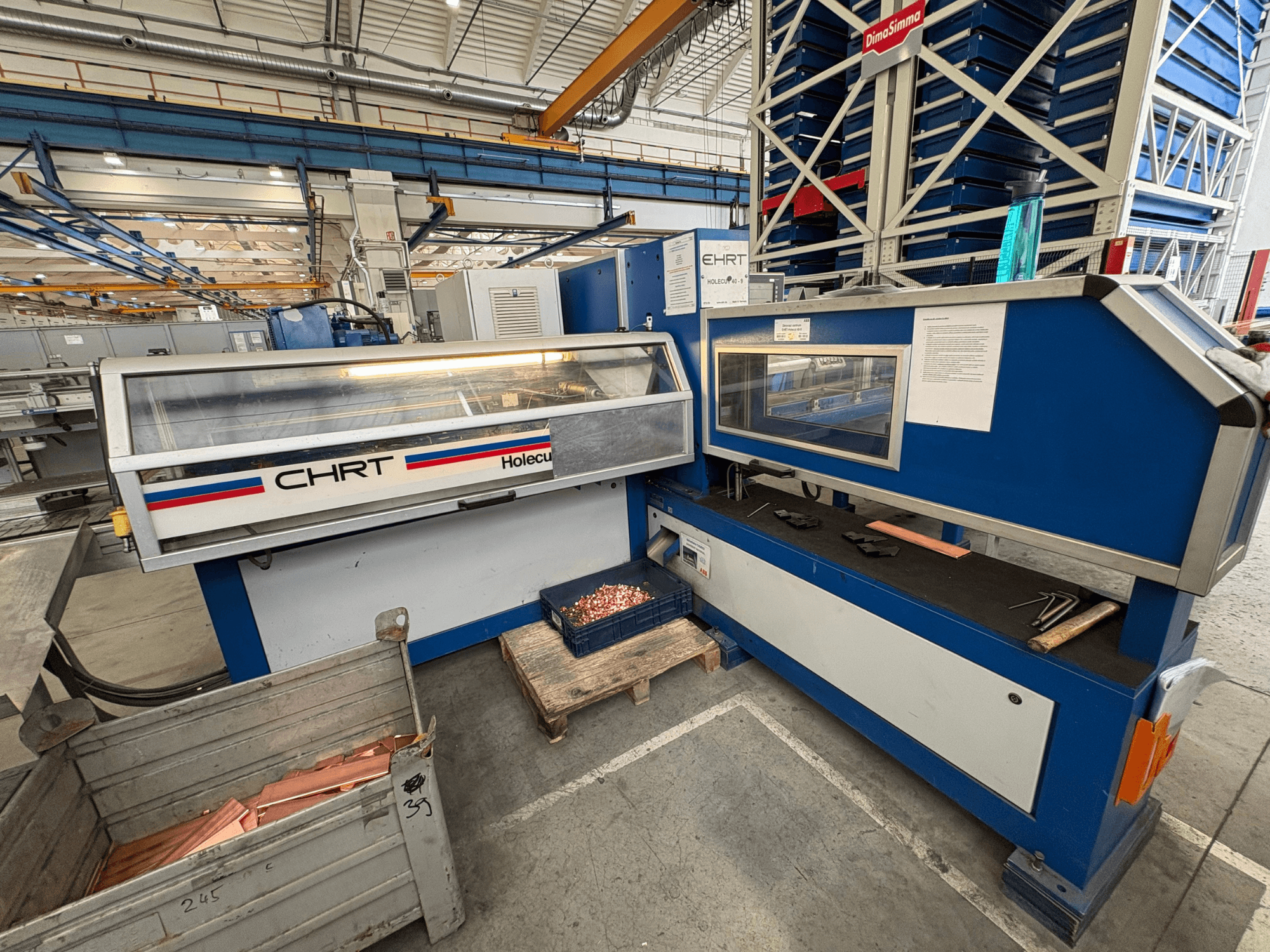 Wykrawarka CNC EHRT Holecut 40-9, widok z przodu, z panelem sterowania, metalowym pojemnikiem i blachami miedzianymi w pobliżu.