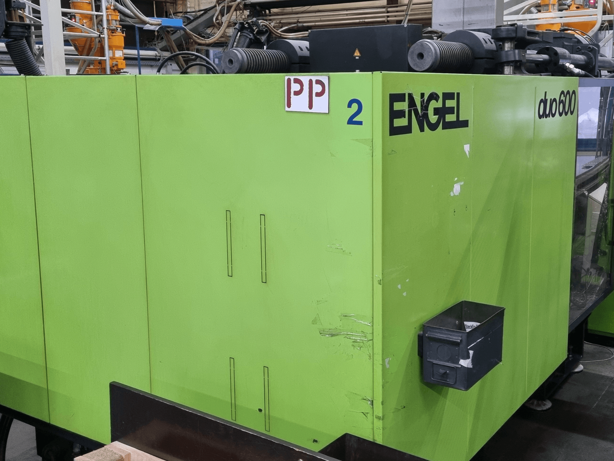 Hydrauliczna wtryskarka Engel duo 600, zielona obudowa, widok z przodu, z oznaczonymi elementami oraz pojemnikiem na materiał.