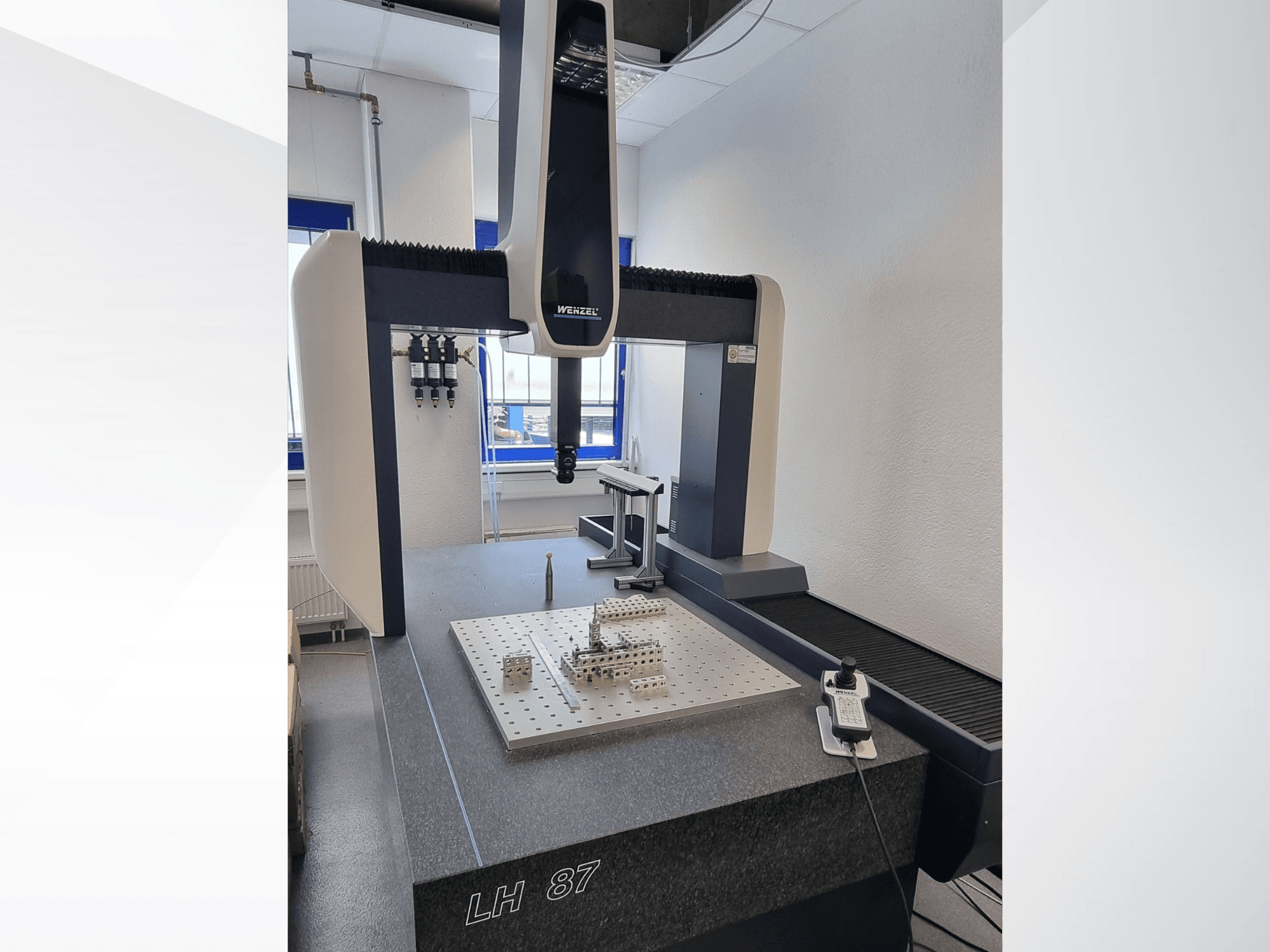 Maszyna CMM Wenzel LH 87 w laboratorium, widok z przodu z sondą pomiarową umieszczoną nad precyzyjną płytą pomiarową oraz widocznym sterownikiem cyfrowym.