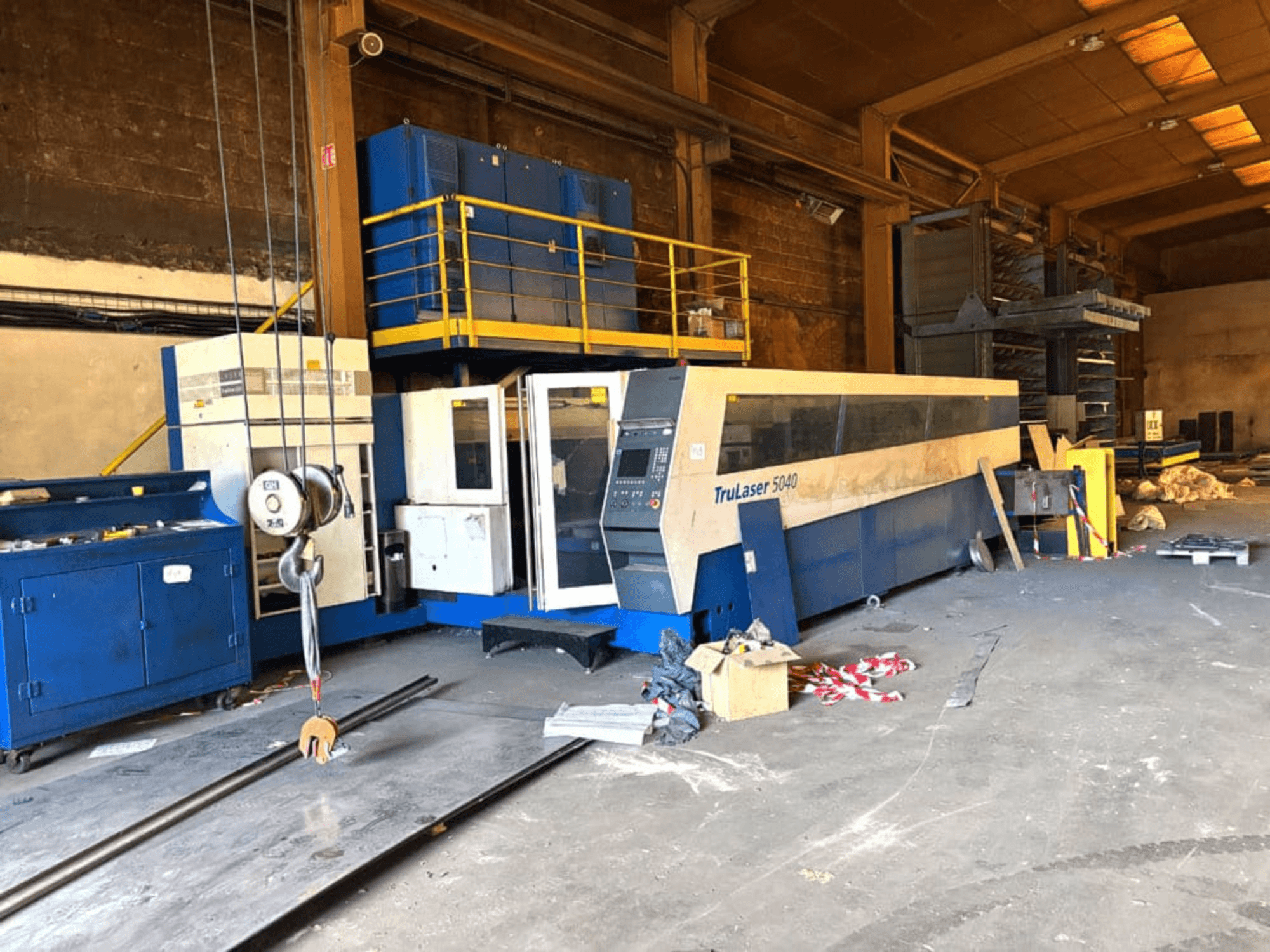 Maszyna do cięcia laserowego CO₂ firmy TRUMPF, model TRULASER 5040, sfotografowana w warsztacie – widok z przodu pod kątem na tle zagraconego pomieszczenia.