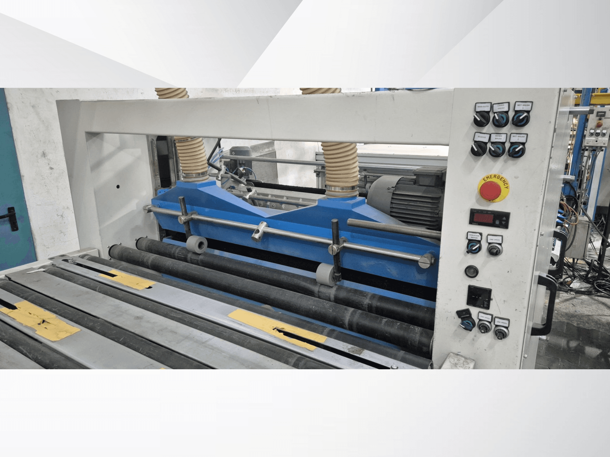 Przemysłowa maszyna rolująca z niebieskimi komponentami, widok z przodu, z panelem sterowania i przyciskiem zatrzymania awaryjnego.