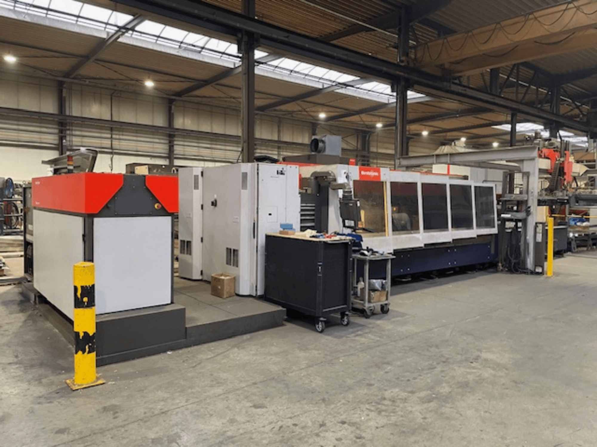 Wycinarka laserowa CO2 Bystronic BySpeed 3015, widok z boku w warsztacie, z wyraźnymi czerwonymi i szarymi elementami konstrukcyjnymi.