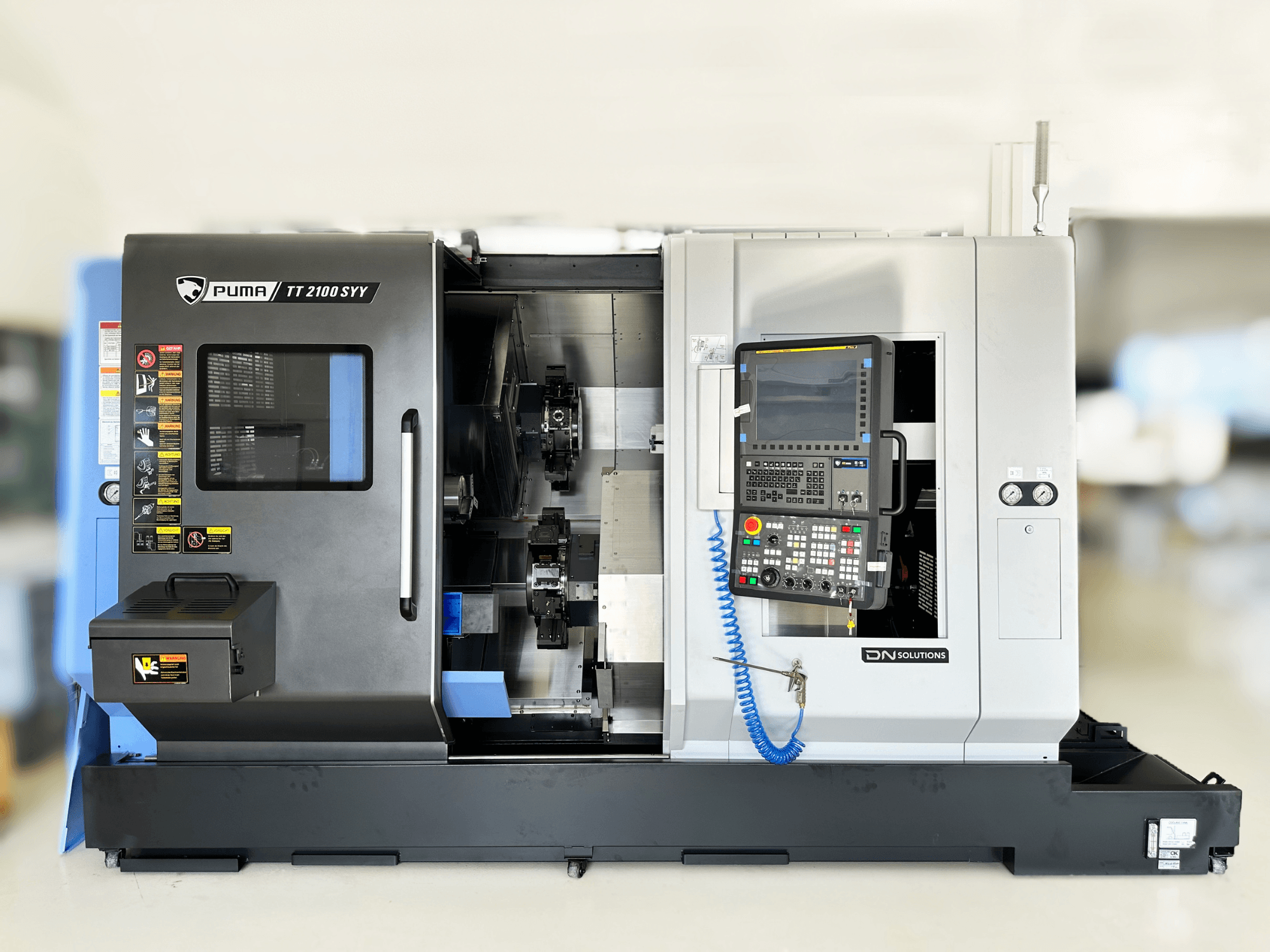 Centrum frezarskie DN SOLUTIONS PUMA TT2100SYY widok z przodu z panelem sterowania i widocznymi elementami wewnętrznymi.