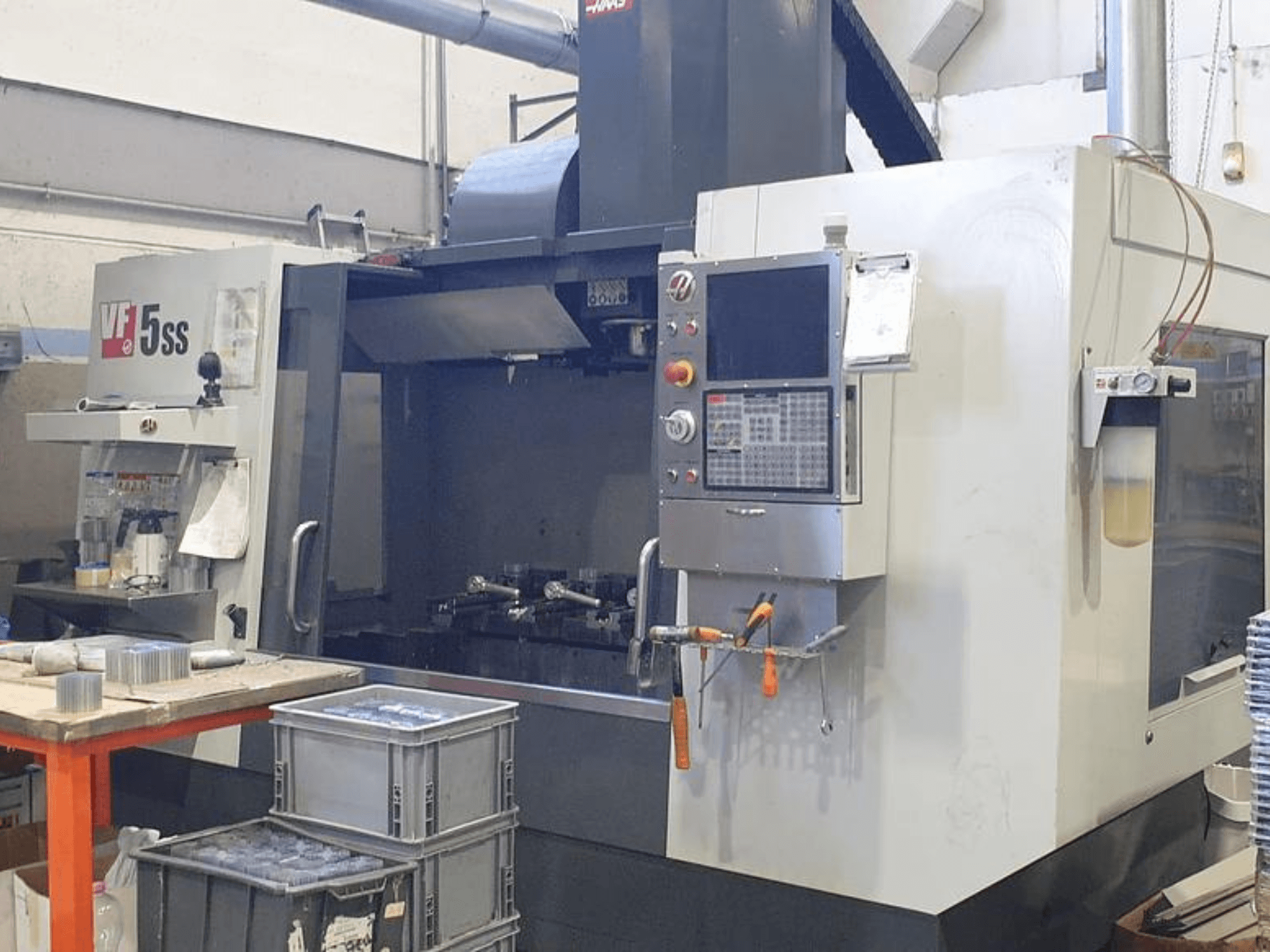 Pionowe centrum obróbcze HAAS VF-5SS w widoku z przodu, pokazujące panel sterowania, obszar roboczy i pojemniki do przechowywania.