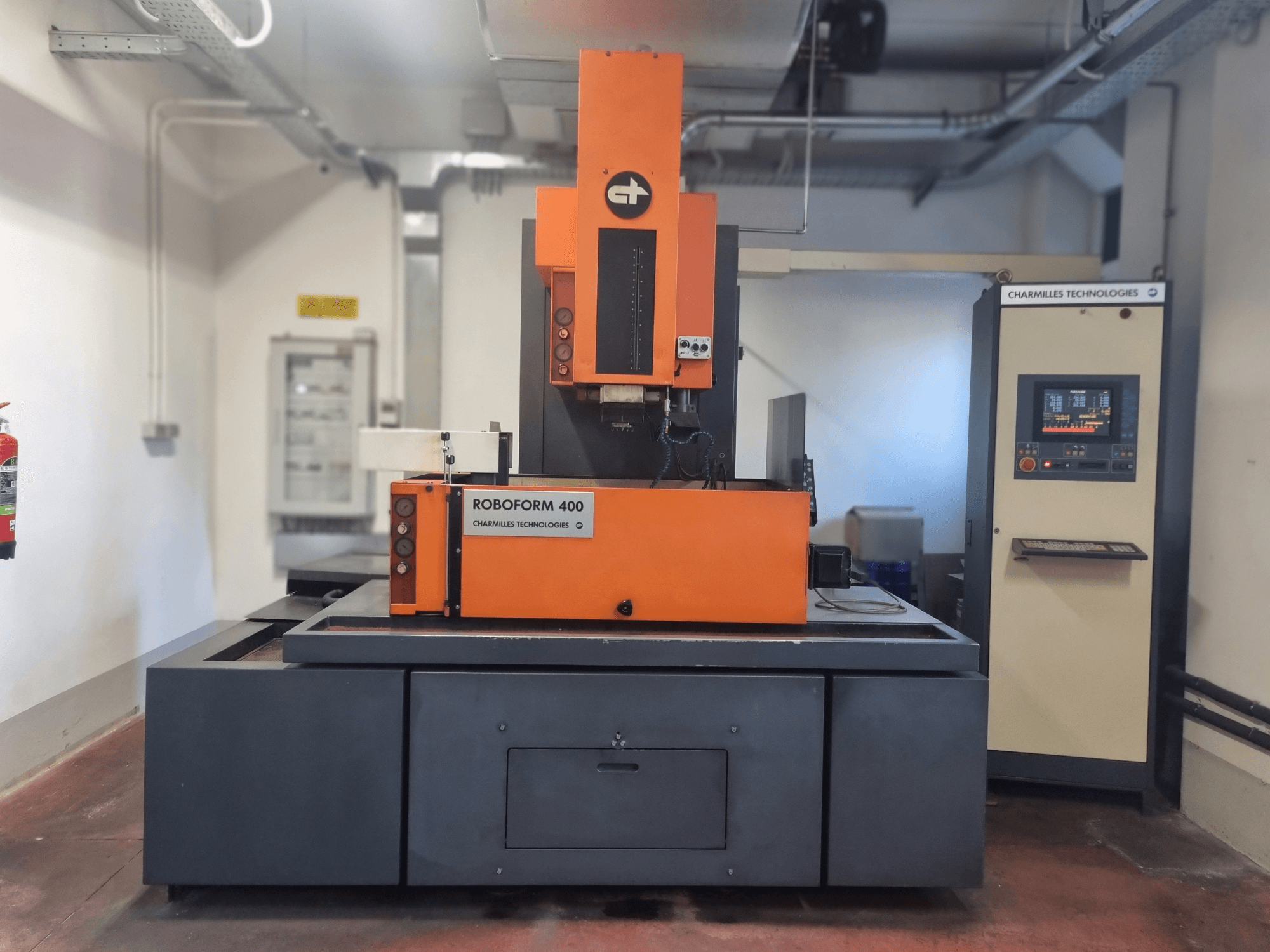 Maszyna Roboforn 400 firmy Charmilles Technologies, widok z przodu, pomarańczowo-szary design, widoczny cyfrowy panel sterowania.