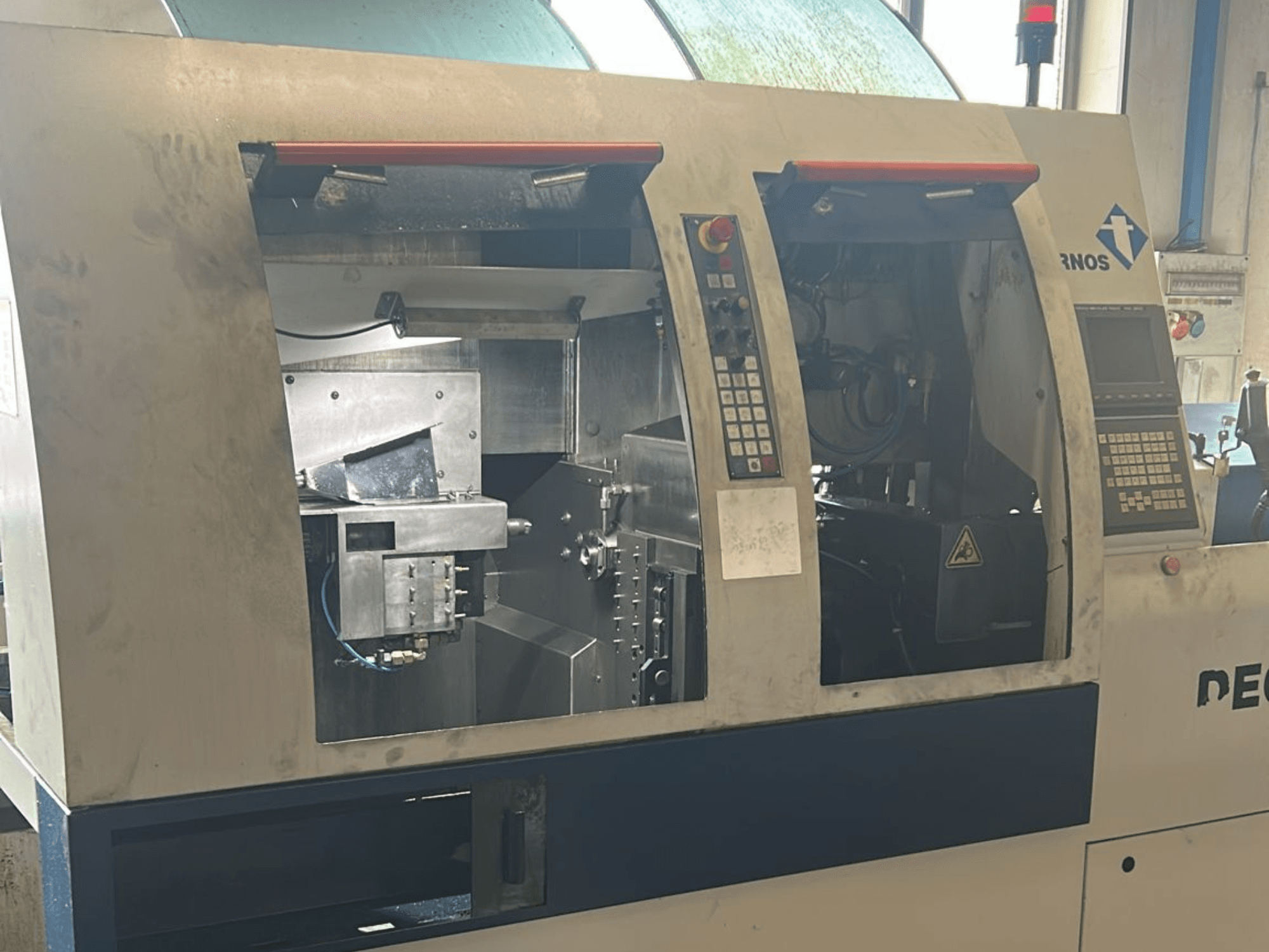 Alt text: Widok z przodu tokarki TORNOS Deco 13 b typu szwajcarskiego z widocznymi panelami sterowania i elementami wewnętrznymi.