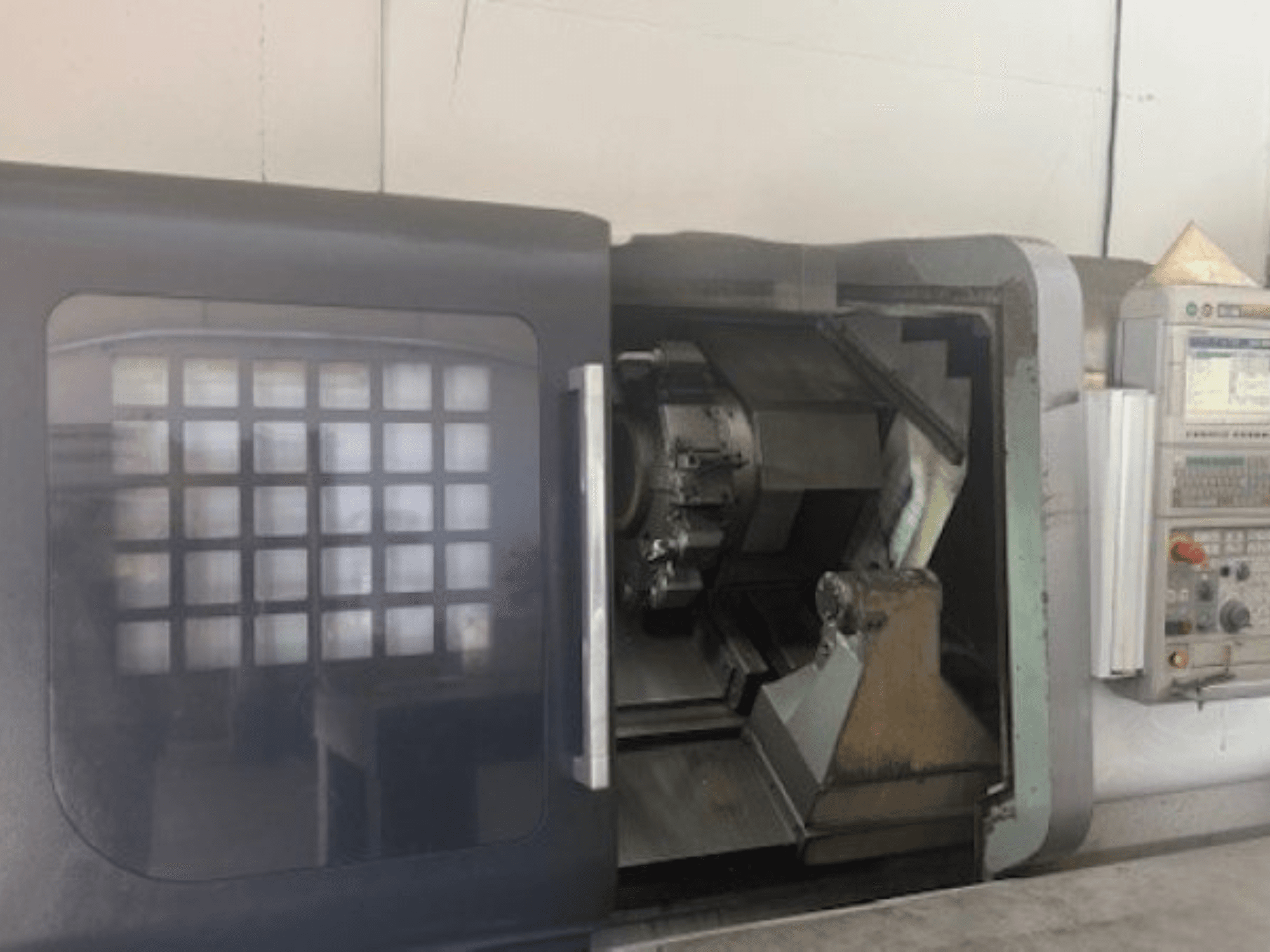Tokarka pozioma MORI SEIKI NLX 2500M, widok z przodu przedstawiający uchwyt narzędziowy, panel sterowania i mechanizm wewnętrzny.