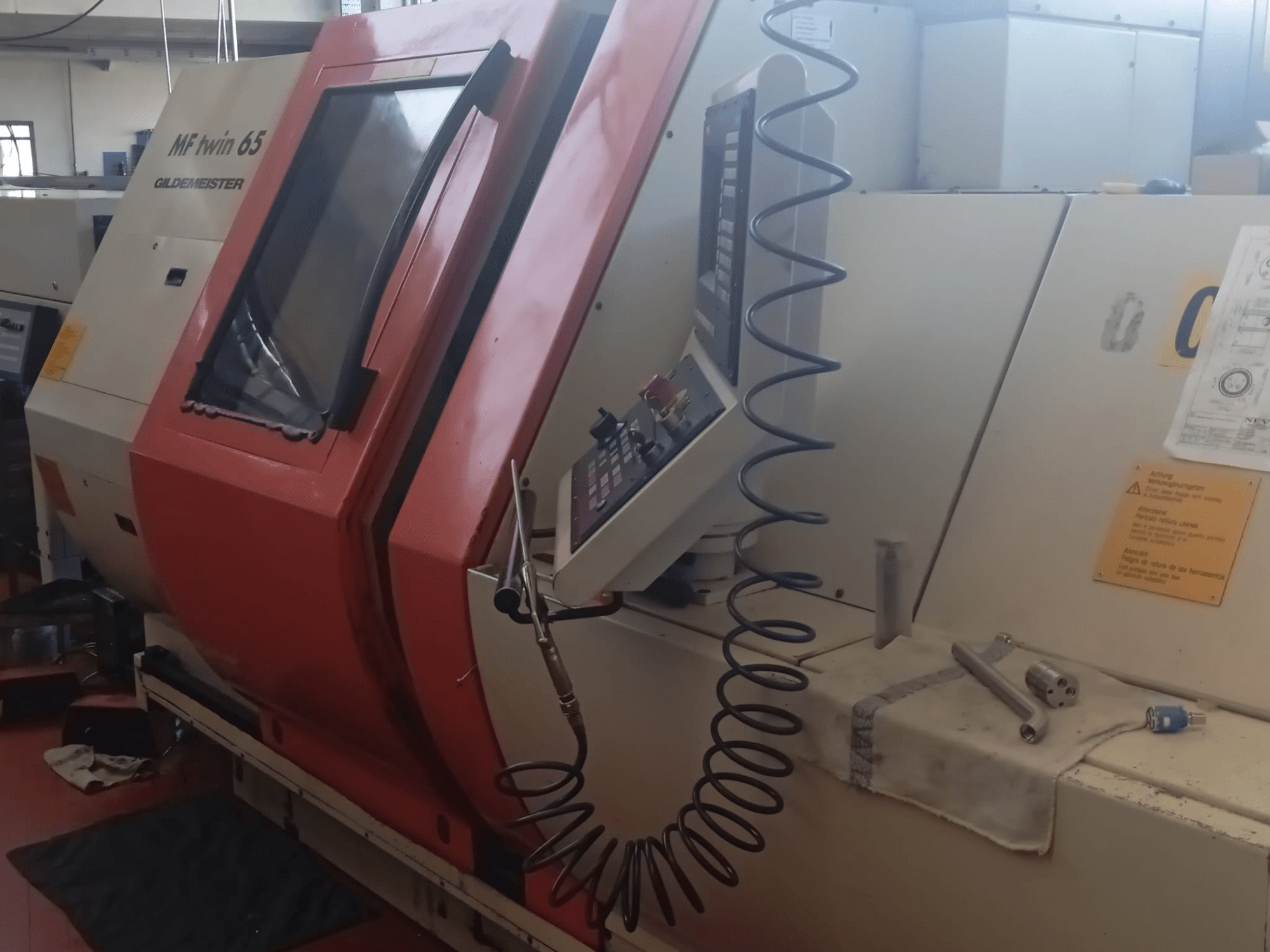 Pomarańczowo-biała maszyna MF twin 65 Gliedemeister, widok z przodu, z panelem sterowania i narzędziami na szmatce.