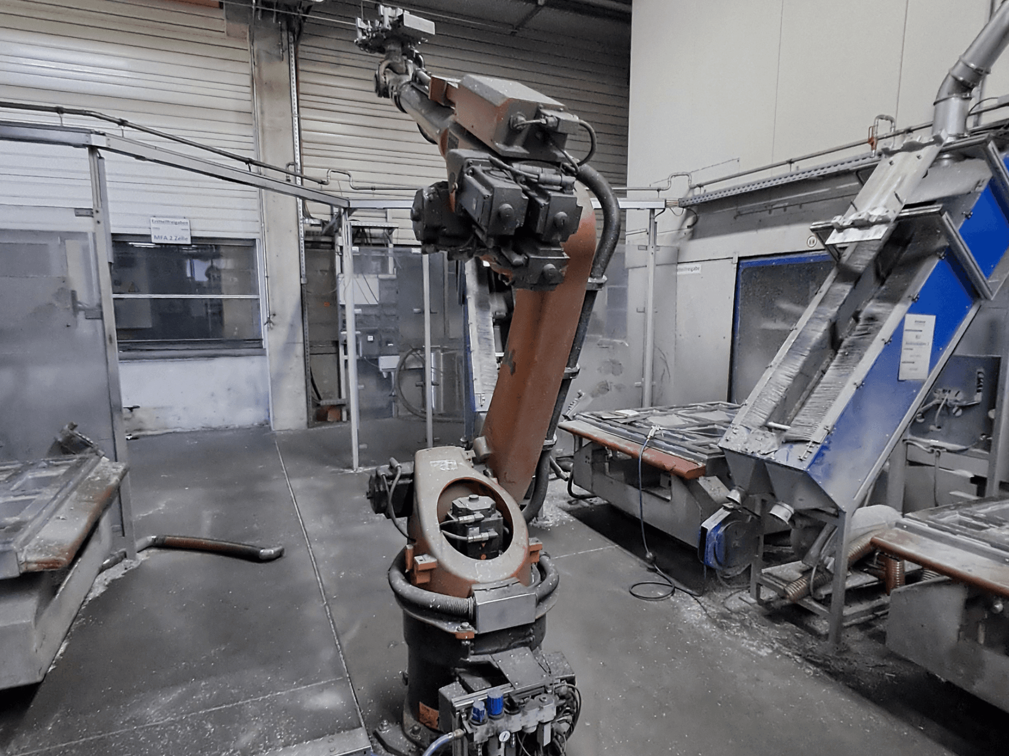 Ramię robota KUKA KR 30L16-2 w środowisku warsztatowym, widok z przodu, z widocznym pyłem i maszynami w tle.