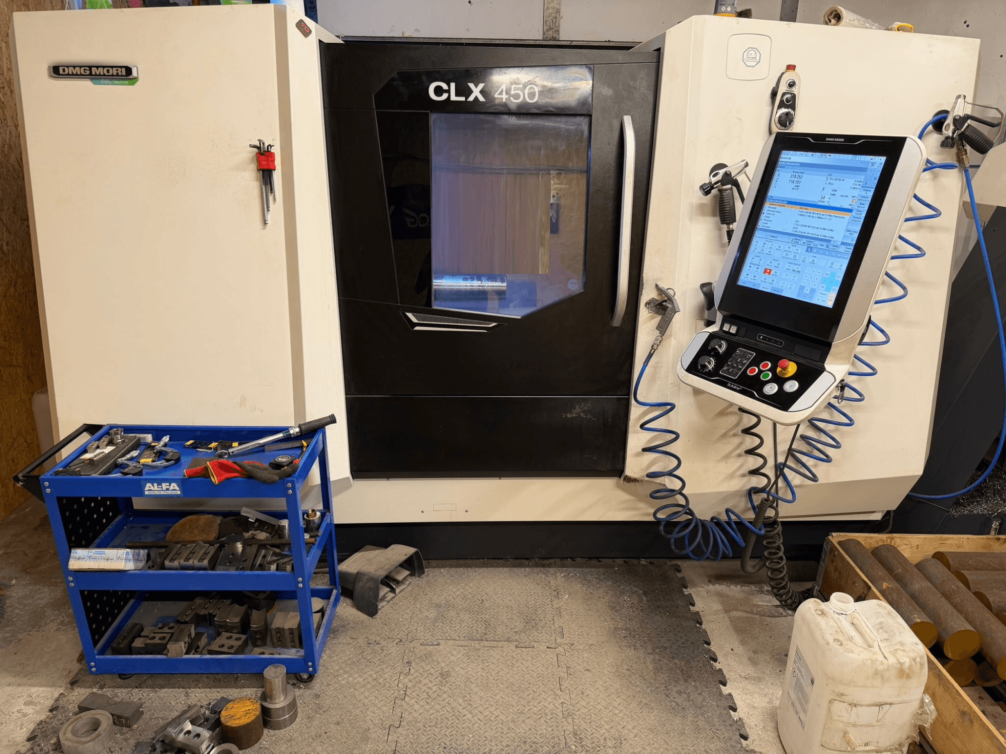 DMG MORI CLX 450 V3 tokarka pozioma widok z przodu, z panelem sterowania i pobliskim wózkiem narzędziowym z wyposażeniem.