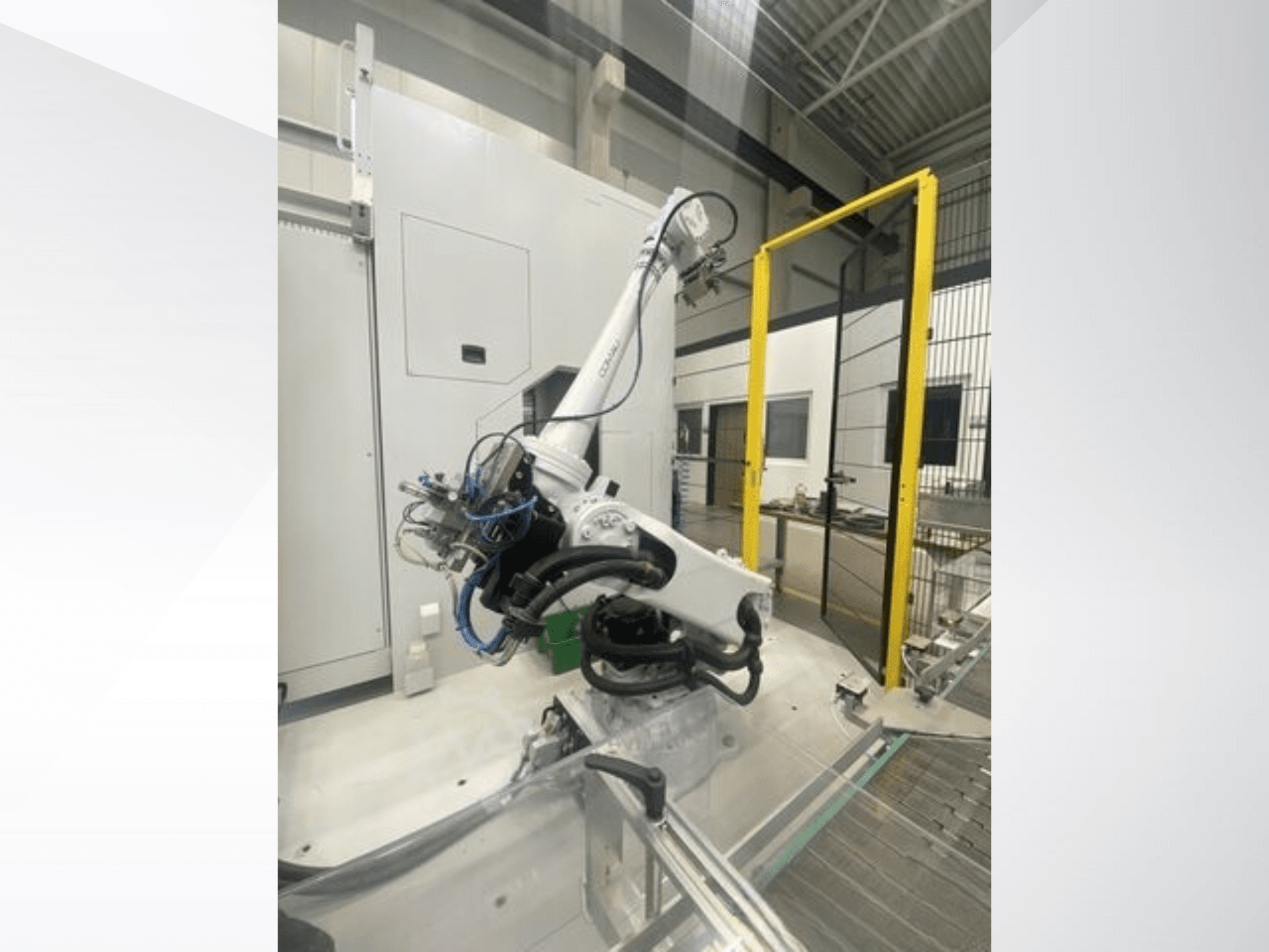 Ramię robota COMAU Smart NJ 40-2.5 w widoku z boku, z kablami i żółtą bramką bezpieczeństwa w ustawieniu fabrycznym.