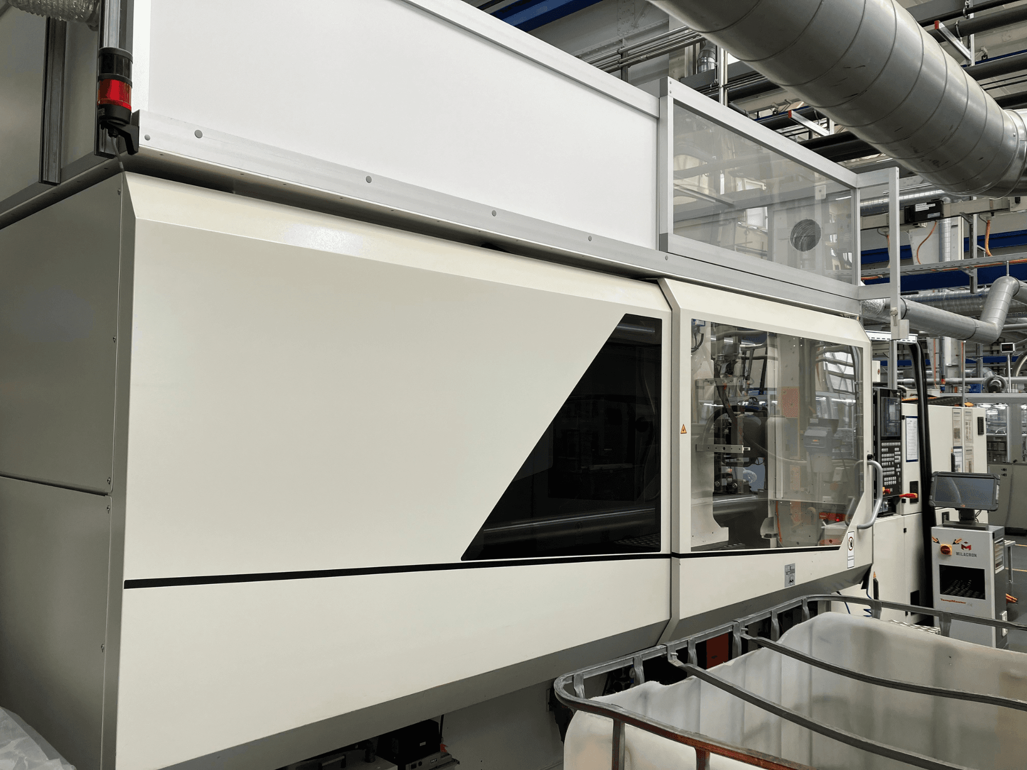 Widok z przodu maszyny przemysłowej z elegancką białą konstrukcją, panelem wyświetlacza i szklaną sekcją zapewniającą widoczność komponentów.