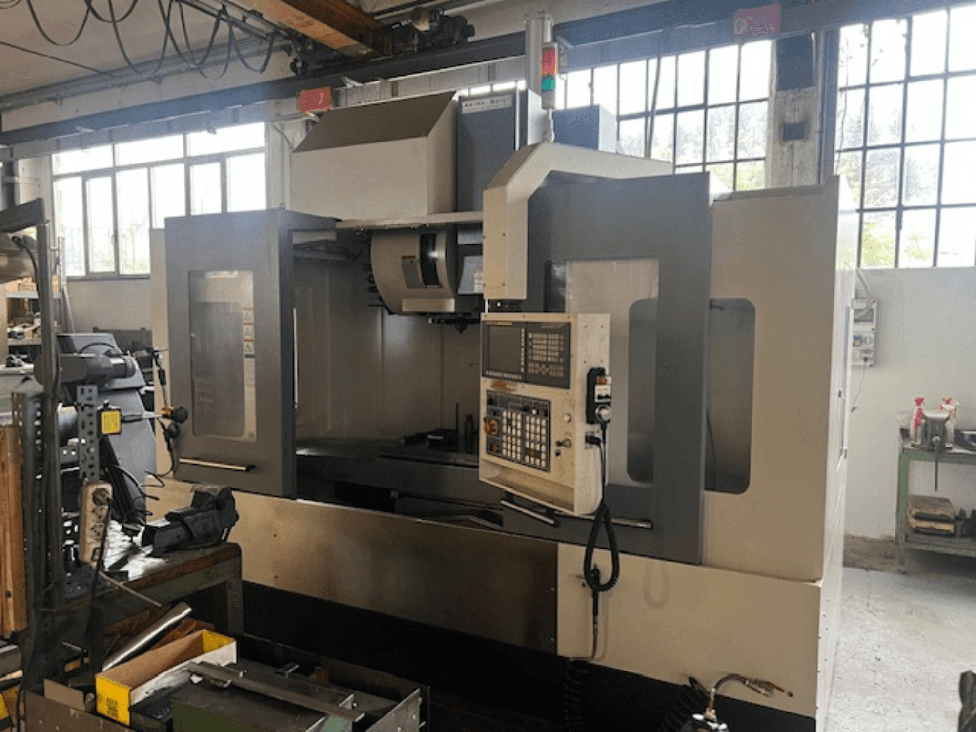 Zaawansowana technologicznie frezarka CNC, widok z przodu, z cyfrowym sterowaniem, podstawowymi wskaźnikami bezpieczeństwa i kompaktową konstrukcją.