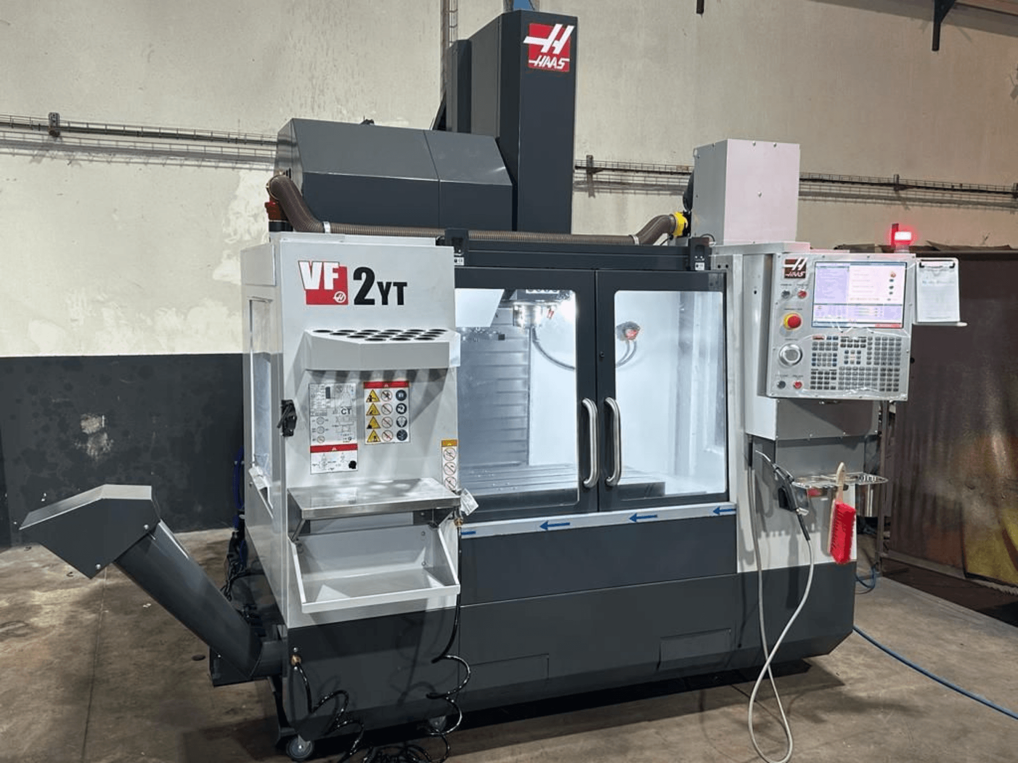 Pionowe centrum obróbcze HAAS VF-2YT-EU – widok z przodu, przedstawiający panel sterowania i schowek na narzędzia.