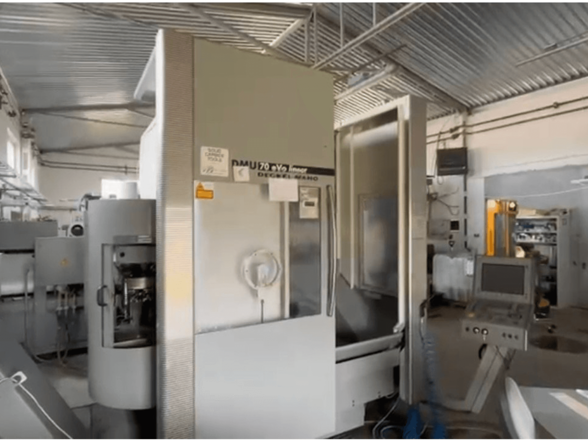 Liniowa maszyna CNC DMU 70 eVo w warsztacie, widok z przodu, z panelem sterowania i nowoczesnym wzornictwem.