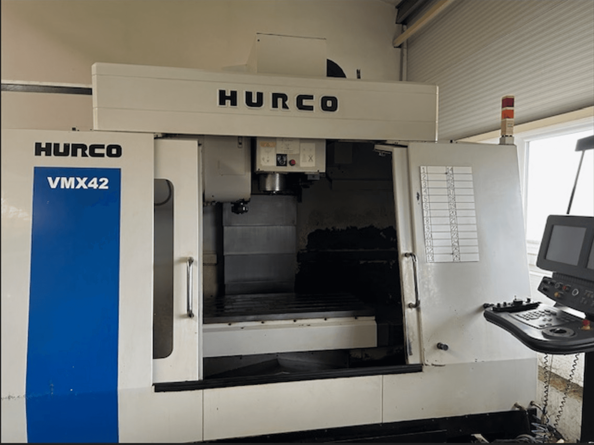 Frezarka CNC Hurco VMX42, widok z przodu, posiada panel sterowania i otwartą przestrzeń roboczą do obróbki.