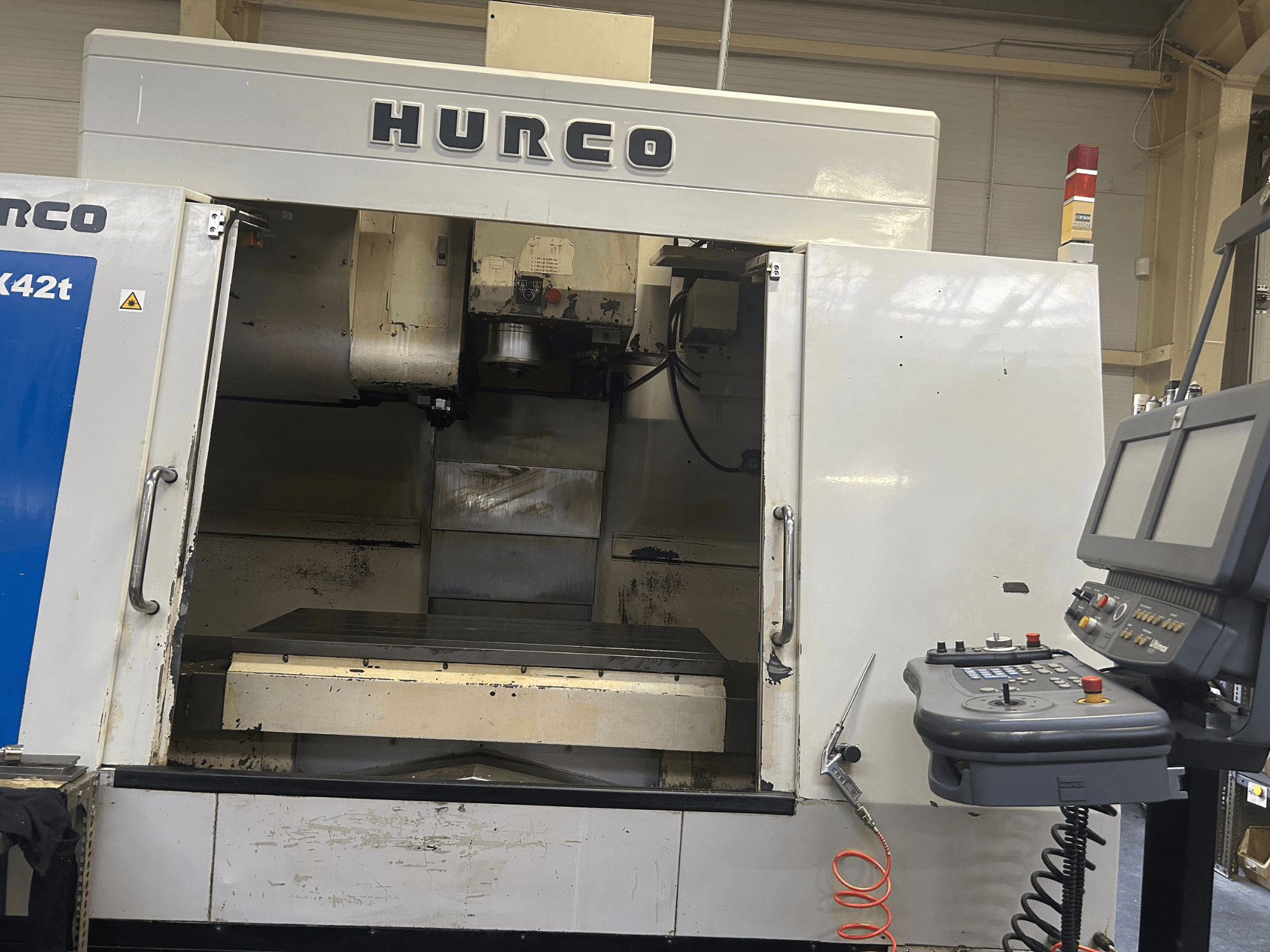Frezarka CNC Hurco VMX42T w widoku z przodu, z otwartą przestrzenią roboczą i panelem sterowania z przyciskami i wyświetlaczem.