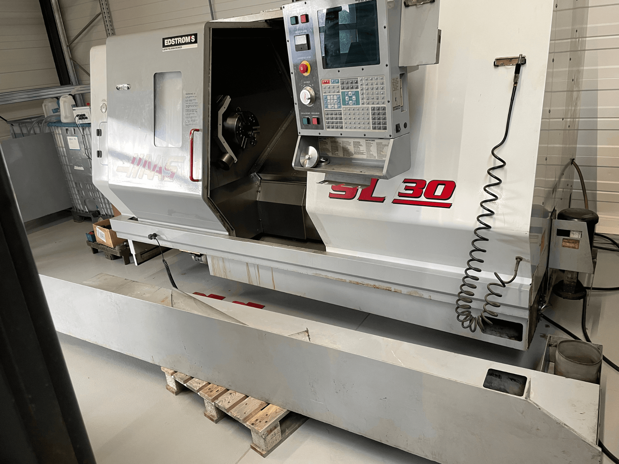 Tokarka CNC Haas SL 30 w warsztacie, widok z boku, z panelem sterowania i otwartym wrzecionem do obróbki.