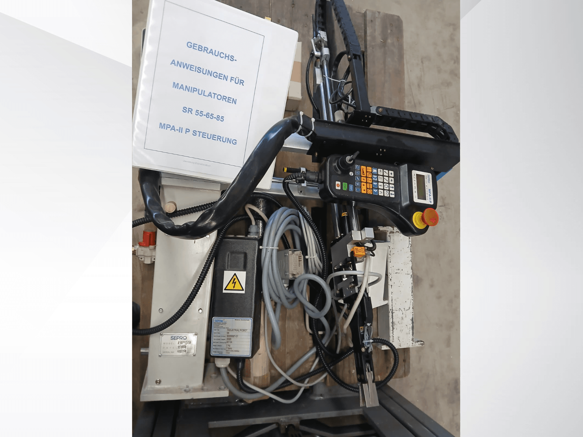 Panel sterowania i komponenty robota bramowego Sepro PIP-55, widziane z boku, z widoczną instrukcją obsługi.