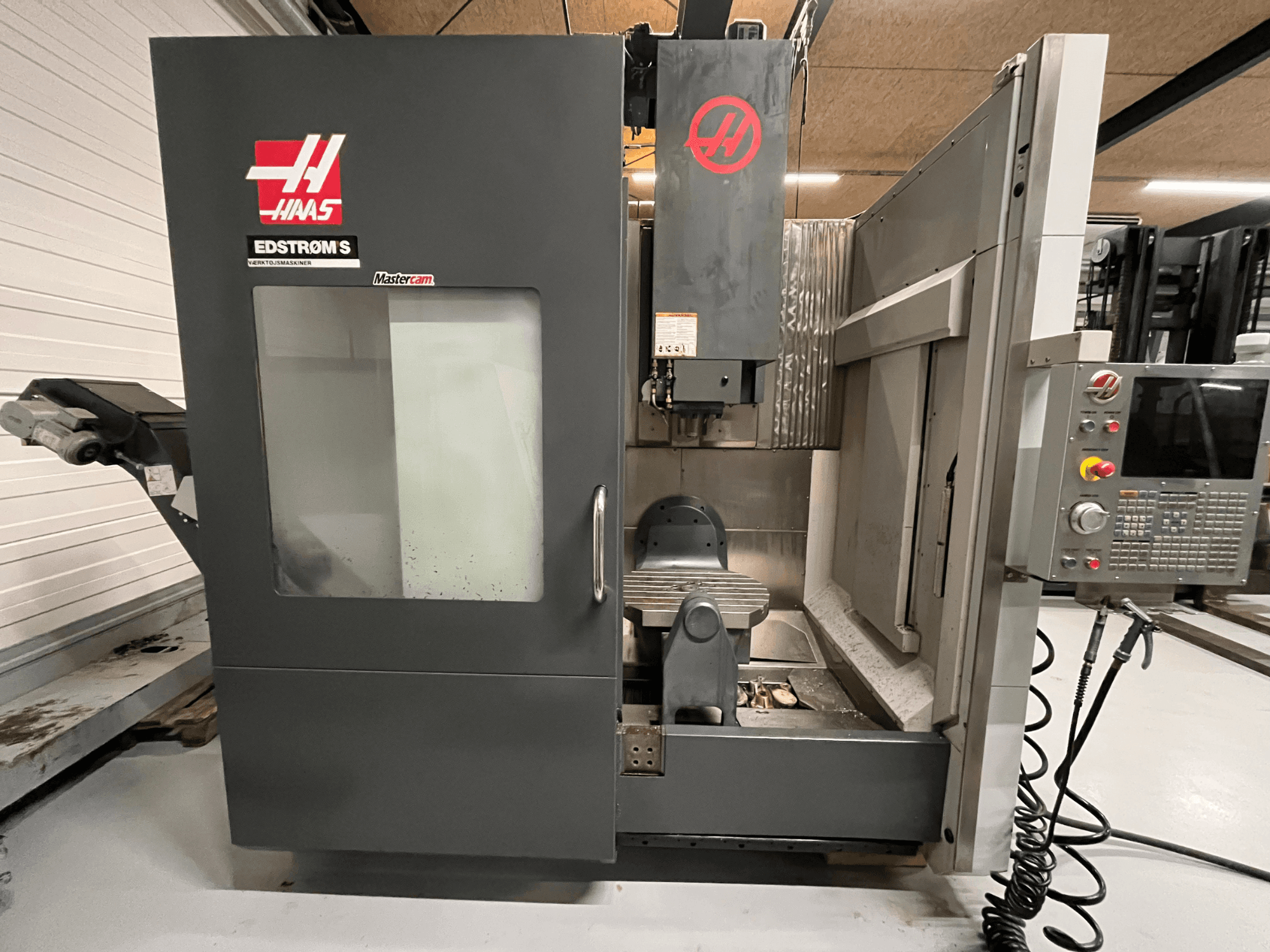 Widok z przodu maszyny CNC Haas EDSTROM S przedstawiający panel sterowania, głowicę wrzeciona i stół obróbczy.