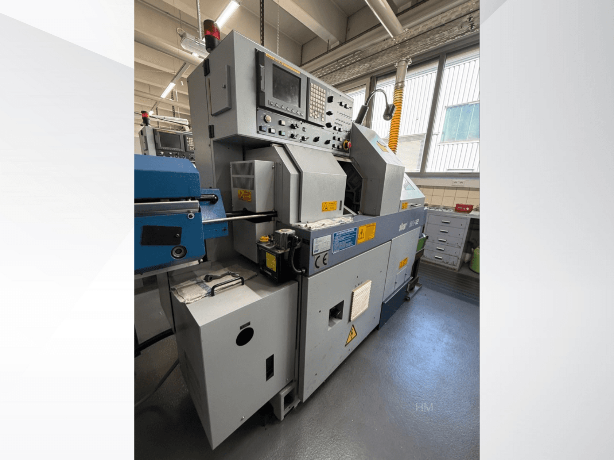 Widok maszyny Lithec 3231 z przodu, pokazujący panel sterowania, silnik i niebieską sekcję podawania w dobrze oświetlonym otoczeniu przemysłowym.