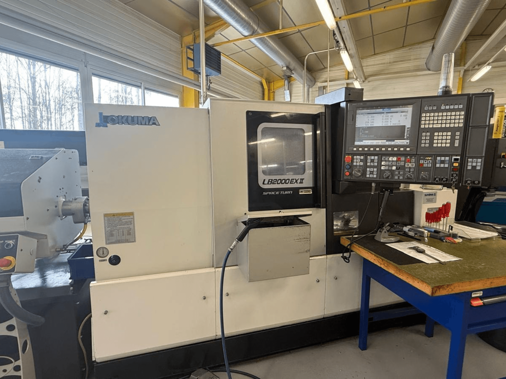 Tokarka pozioma Okuma LB2000EX II, widok z przodu; zawiera panel sterowania, obszar wrzeciona i otaczający obszar roboczy.