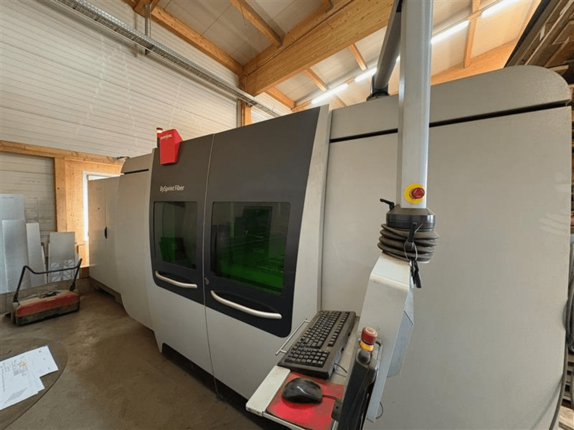 Maszyna do cięcia Bystronic ByJet Fiber w warsztacie, widok z przodu pokazujący panel sterowania i podwójne zielone okna podglądu.