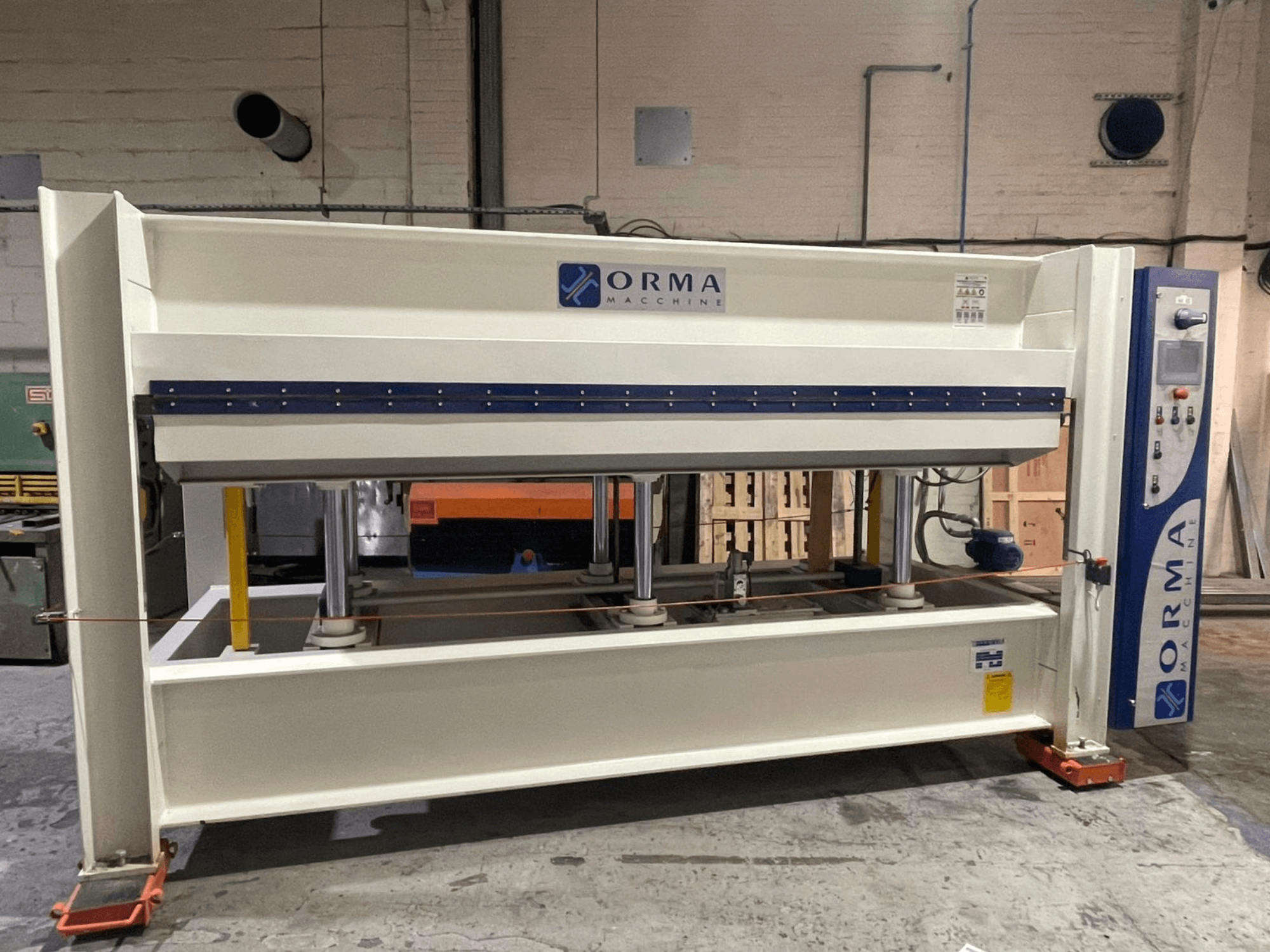 Prasa hydrauliczna ORMA, widok z przodu, ze srebrnym wykończeniem, panelem sterowania po prawej stronie i pionowymi tłokami do prasowania.