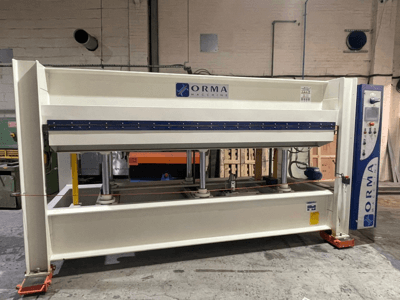 Prasa hydrauliczna ORMA, widok z przodu, ze srebrnym wykończeniem, panelem sterowania po prawej stronie i pionowymi tłokami do prasowania.