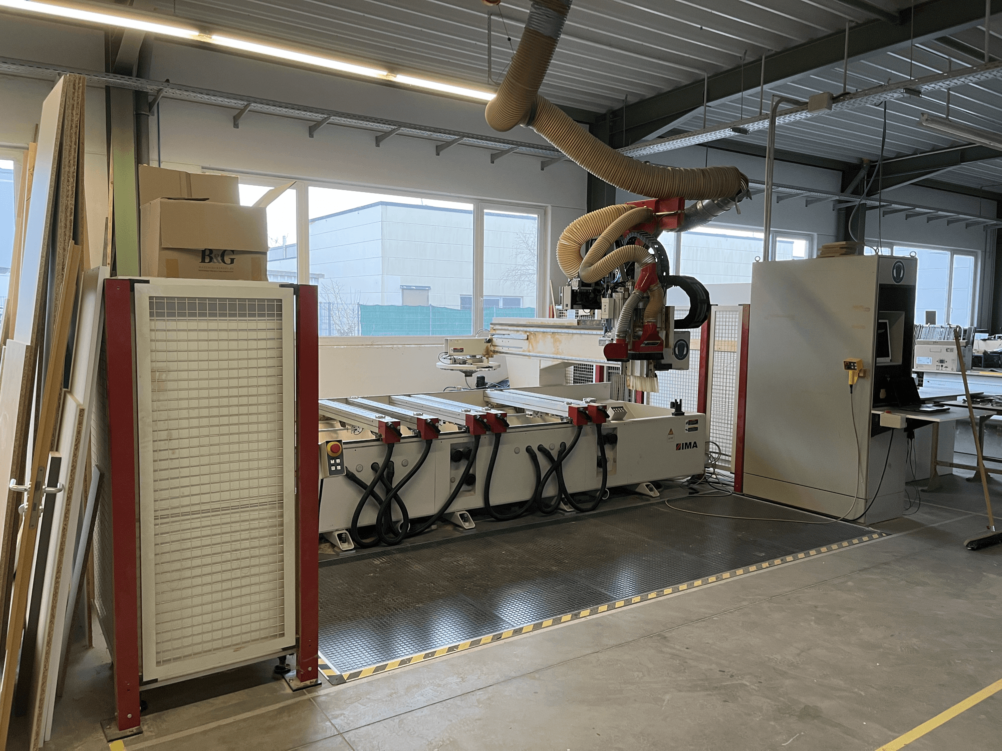 Centrum obróbcze CNC do drewna IMA BIMA 410 w warsztacie, widok z boku z widocznym panelem sterowania i systemem odpylania.